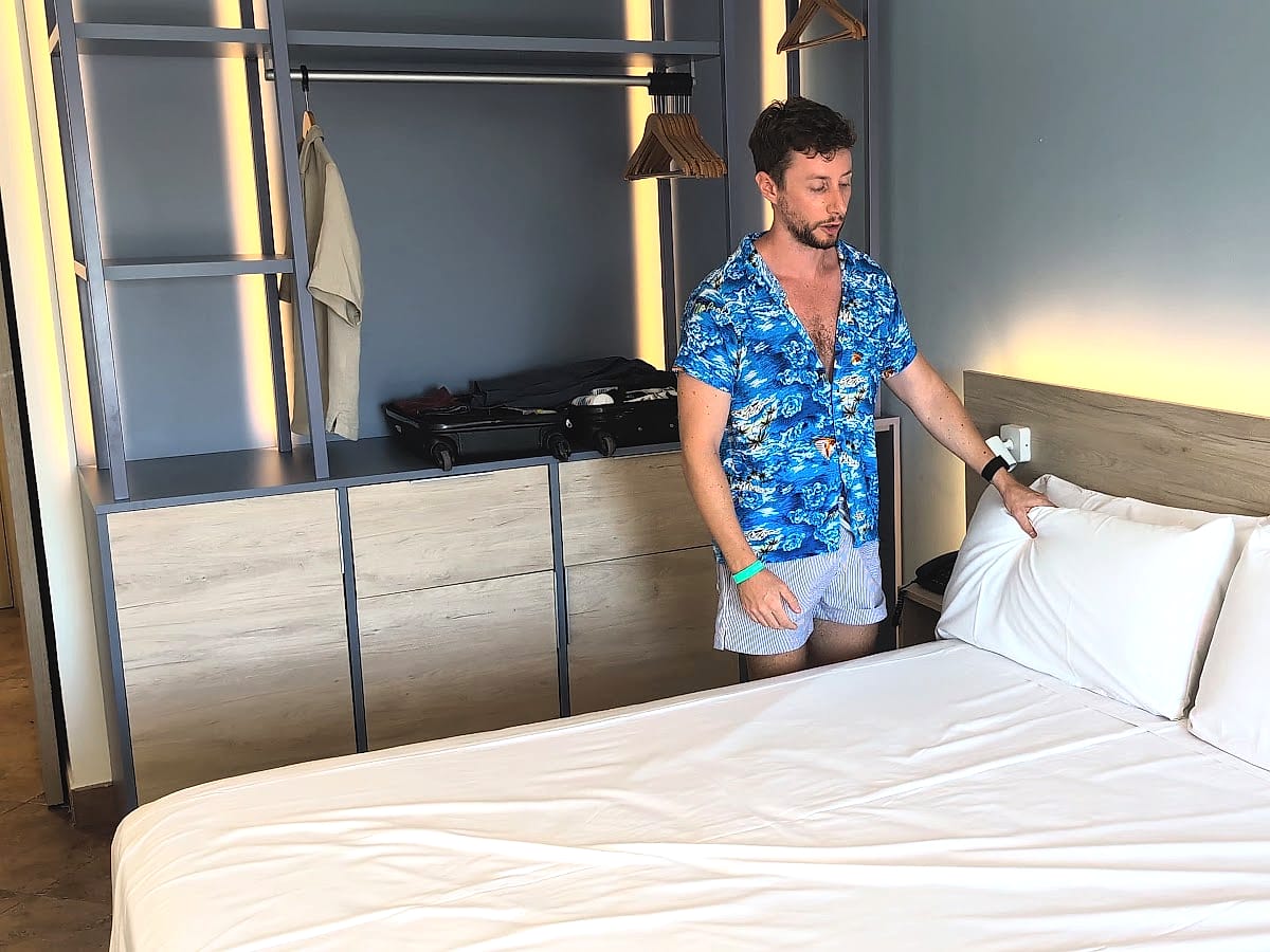 Javier Sobrino junto a la cama de la habitación del Alegría Colonial Mar, con las almohadas y el armario