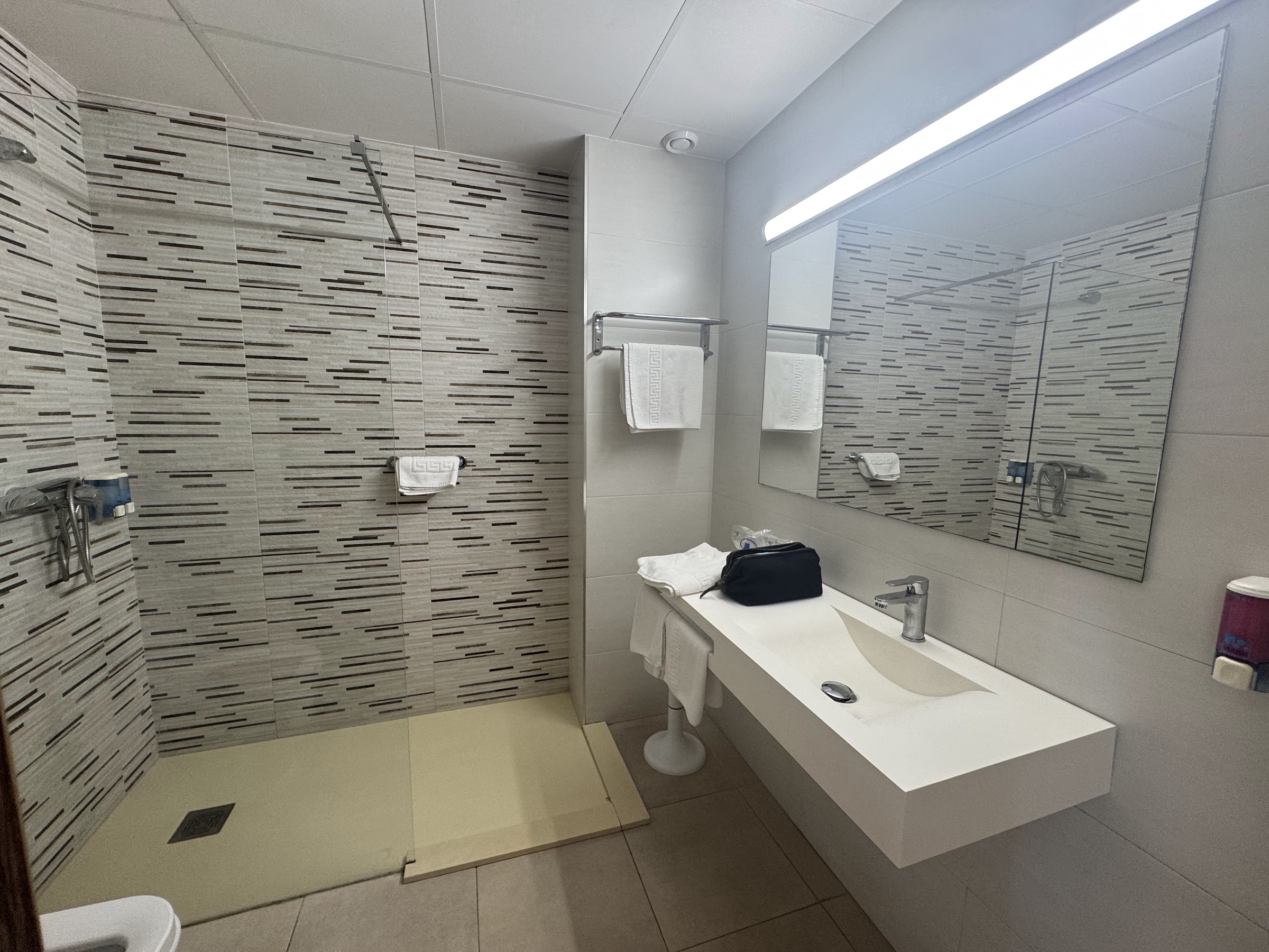Baño reformado del Hotel Alone Benidorm con ducha a ras de suelo y lavabo suspendido