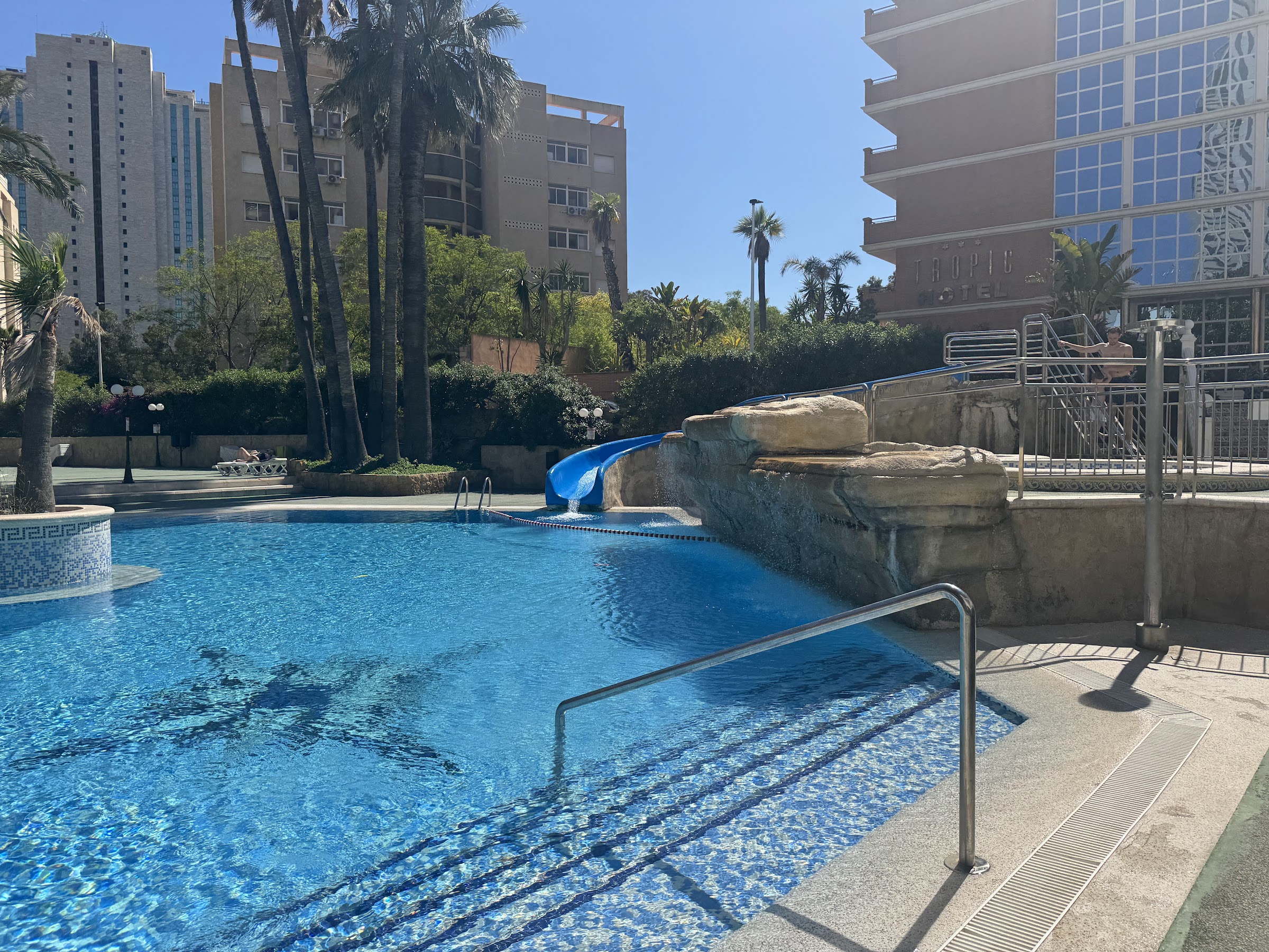 Piscina con tobogán y palmeras del Hotel Tropic, que comparten los clientes del Hotel Alone en Benidorm