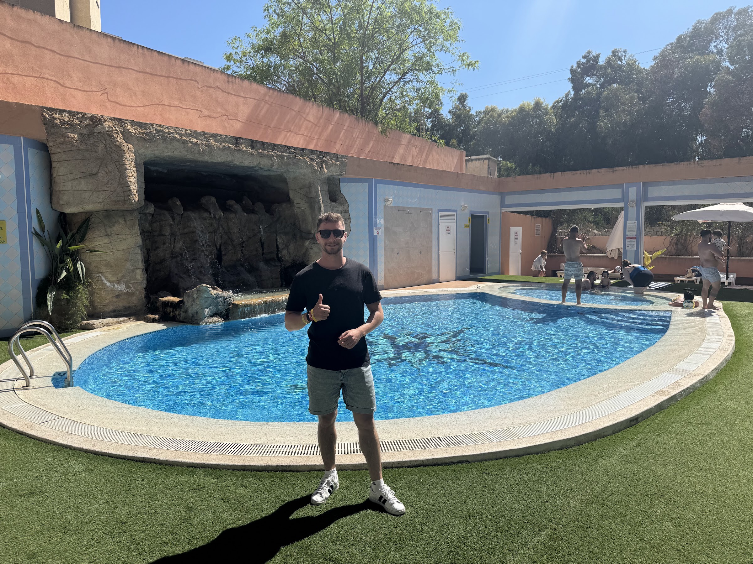 Piscina con cascada y piscina infantil al fondo en el Hotel Alone Benidorm