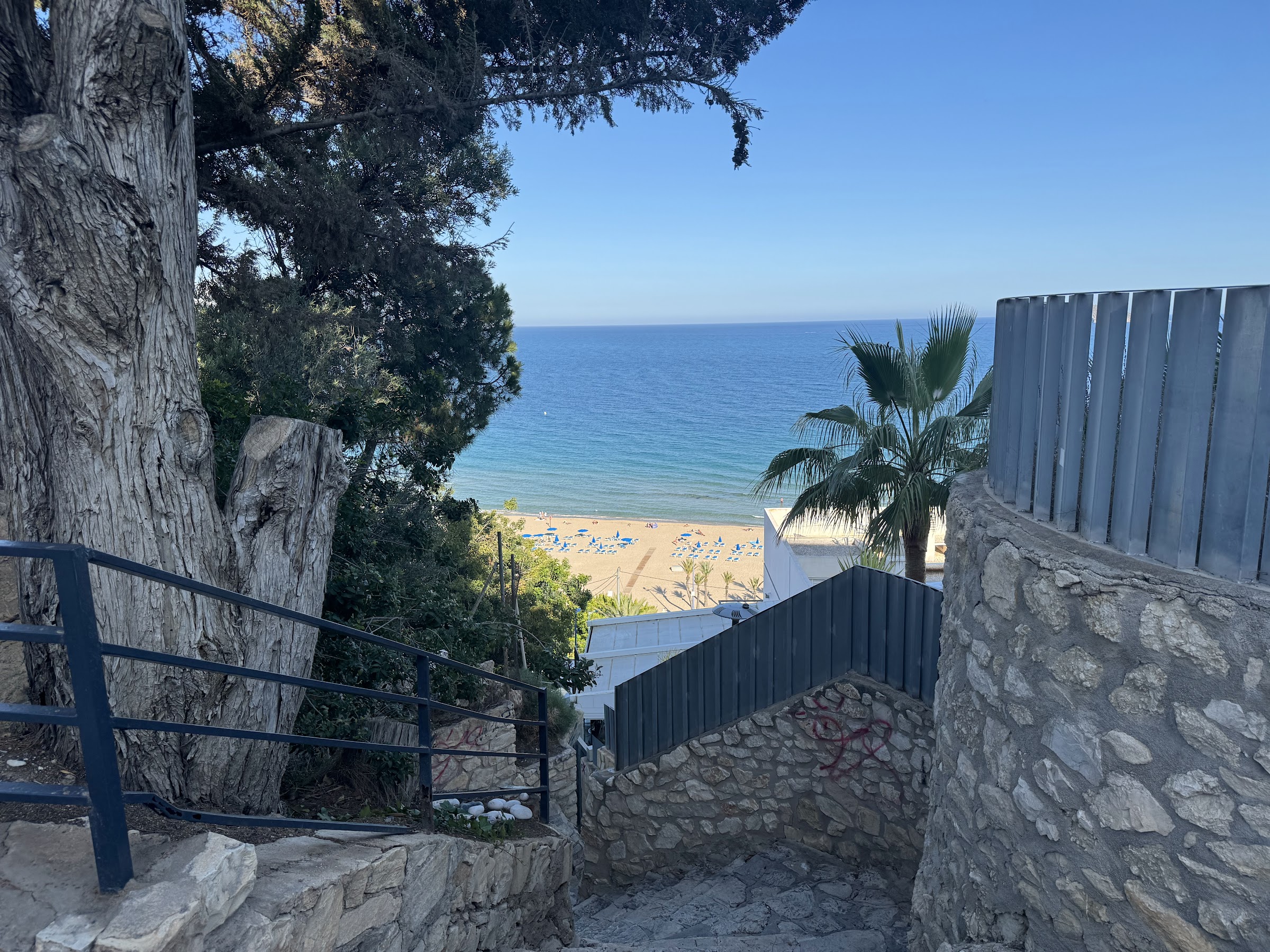 Escaleras de bajada a la playa cerca del Hotel Alone, con el mar de Benidorm al fondo