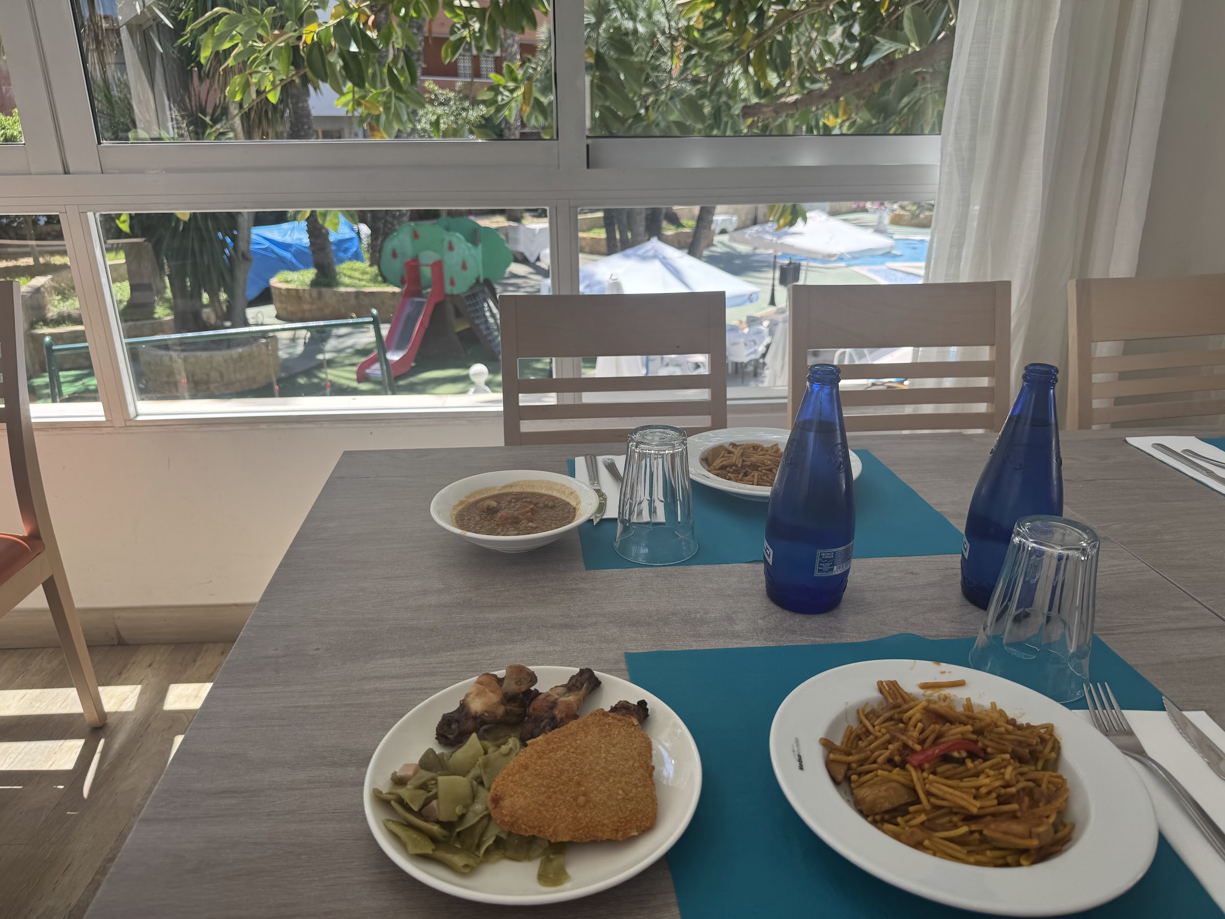 Mesa del comedor del Hotel Alone Benidorm con agua incluida y vistas al jardín