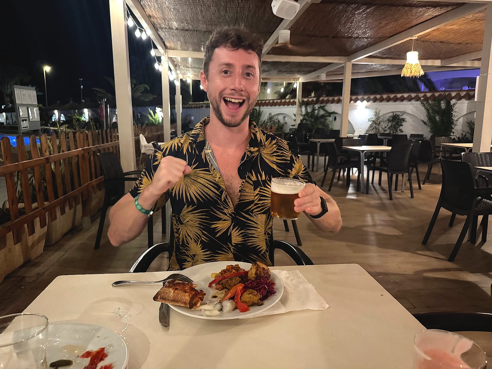 Javier Sobrino cenando en la terraza del Alua Golf Trinidad, con un plato de carne y una cerveza