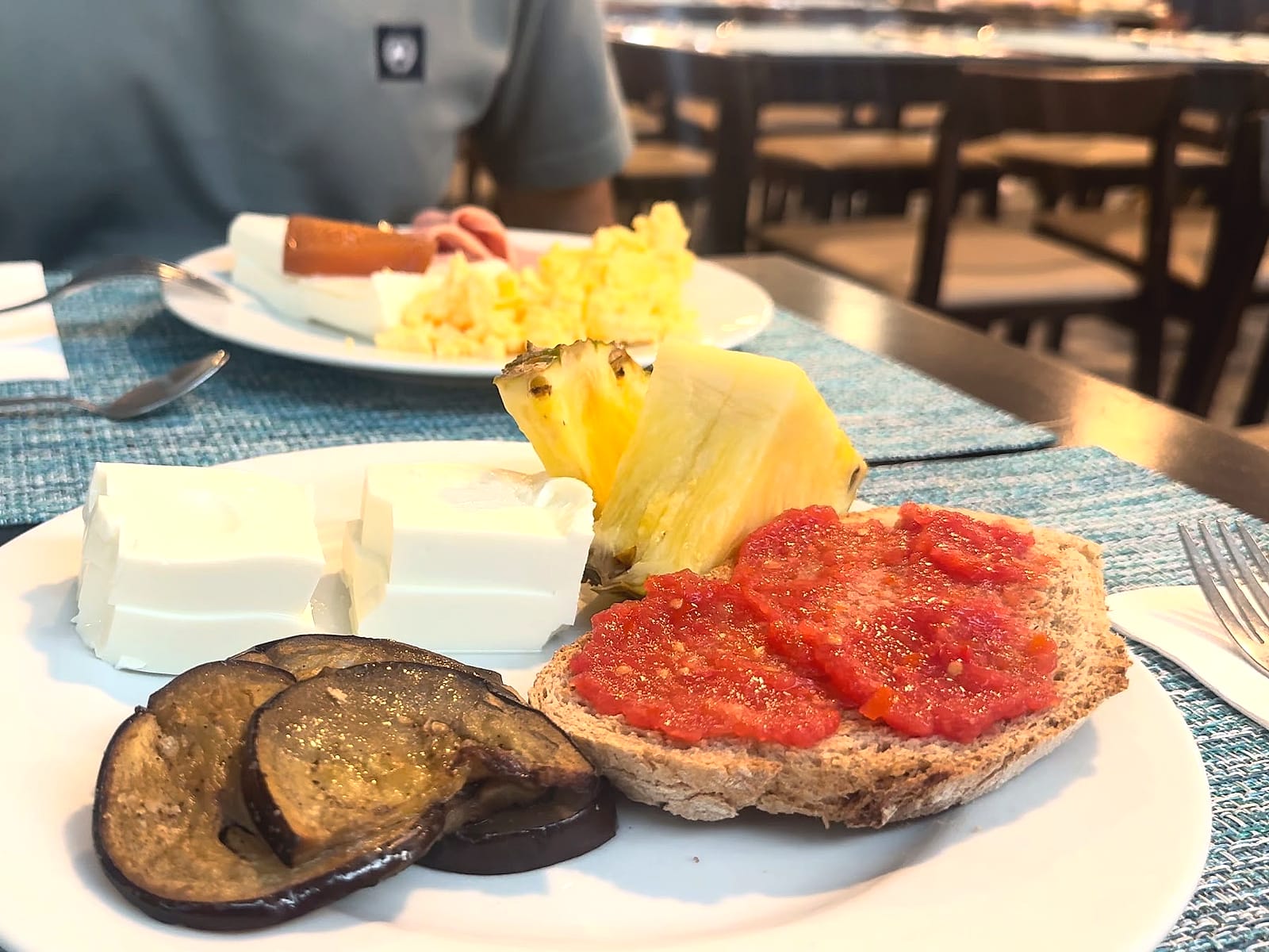 Un plato del desayuno del Alua Golf Trinidad, con tostada con tomate, queso fresco, berenjena y piña