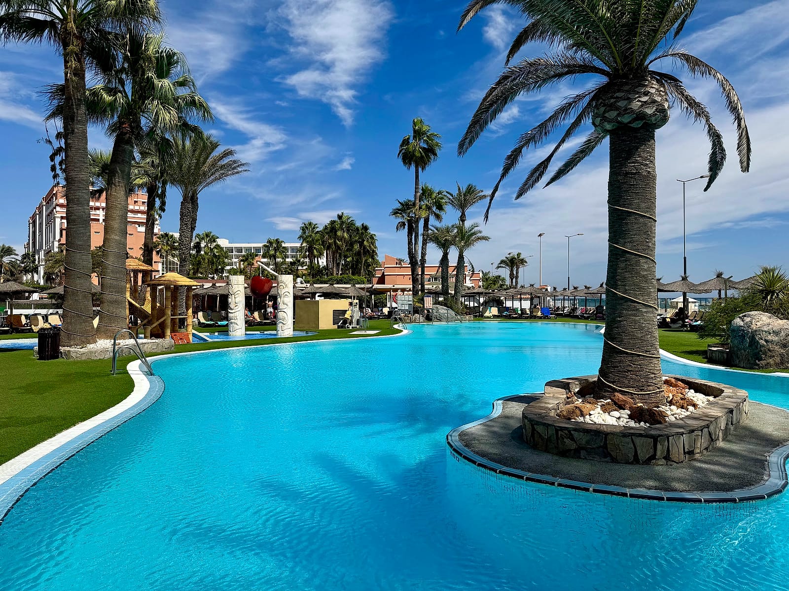La piscina grande del Alua Golf Trinidad, con una isleta con palmera en el centro