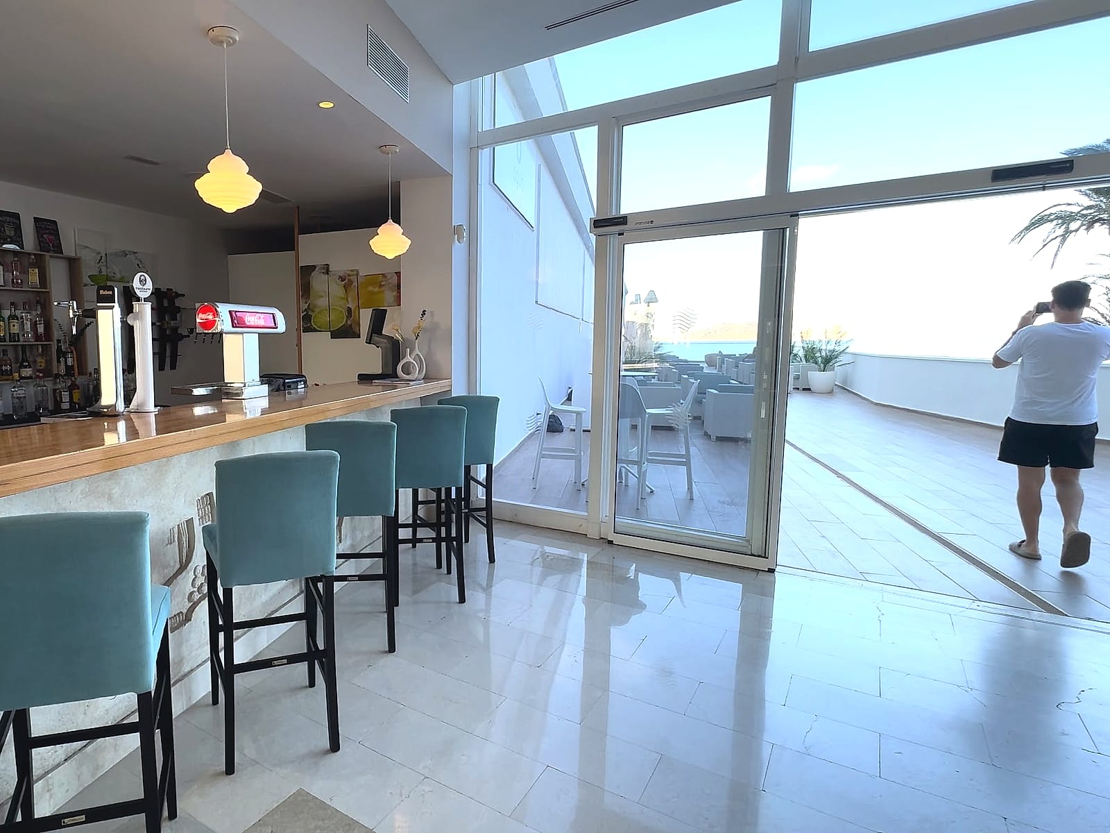 La cafetería del AluaSun Doblemar, con taburetes y ventanales hacia el mar