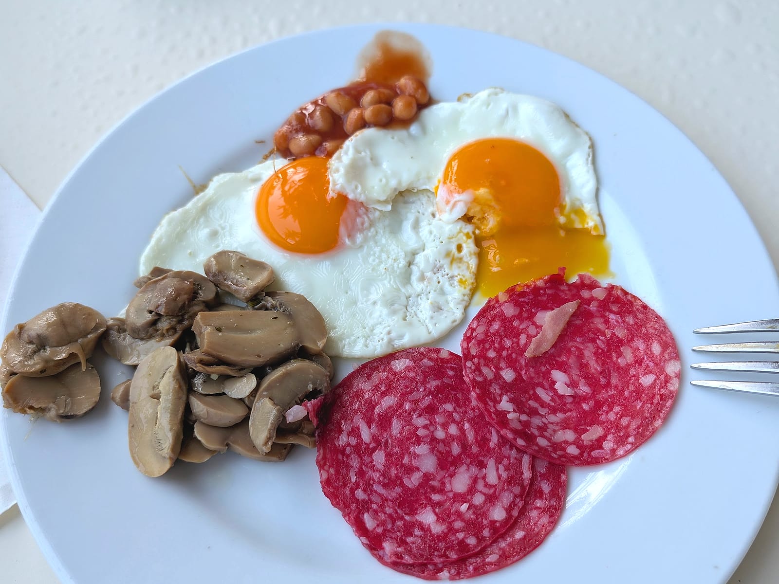 Un plato del desayuno del AluaSun Doblemar, con huevos fritos, judías, champiñones y salchichón