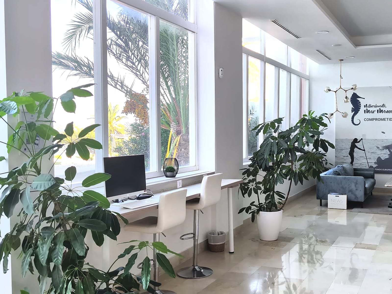 El vestíbulo del AluaSun Doblemar, renovado, con sofás, plantas y ventanales
