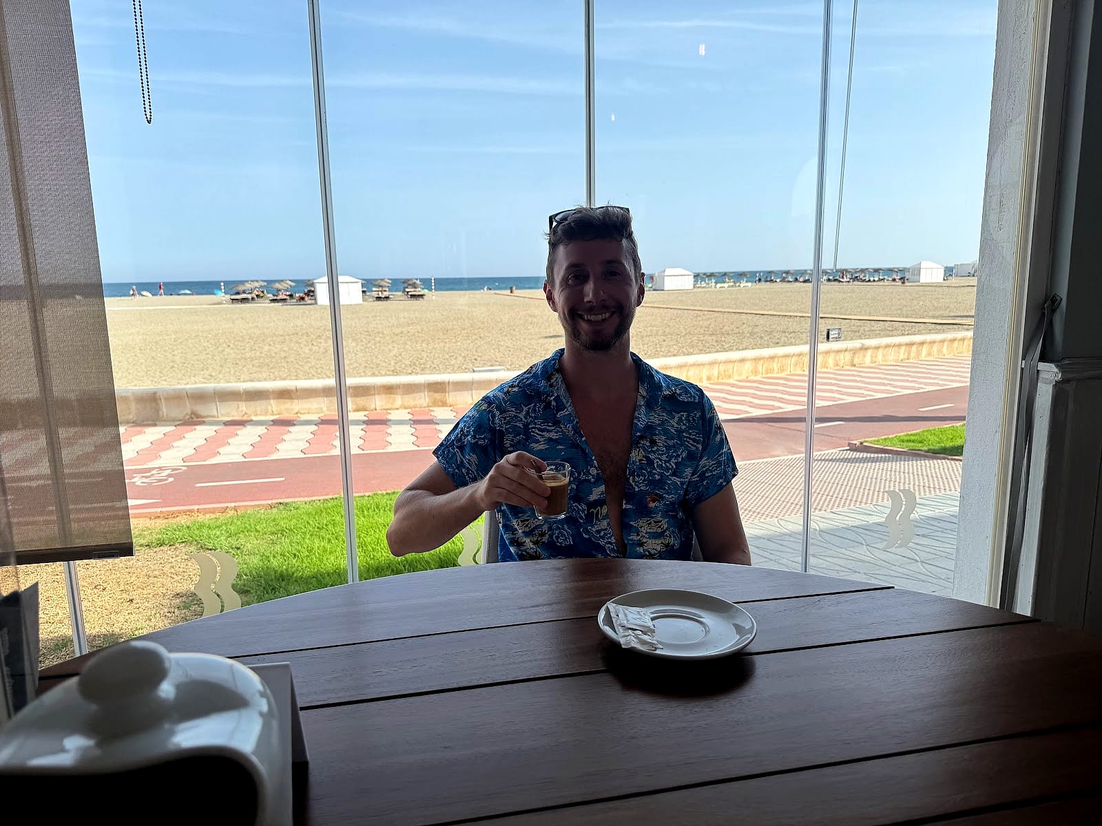 Javier Sobrino tomando un café en el restaurante del Hotel Bahía Serena, con la playa detrás del cristal