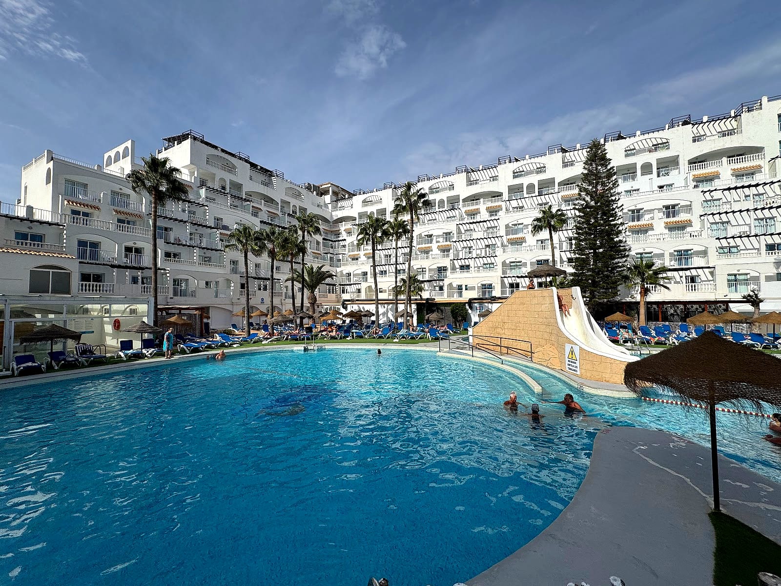 La piscina principal del Hotel Bahía Serena, en el centro del edificio en forma de U, con los toboganes a la derecha