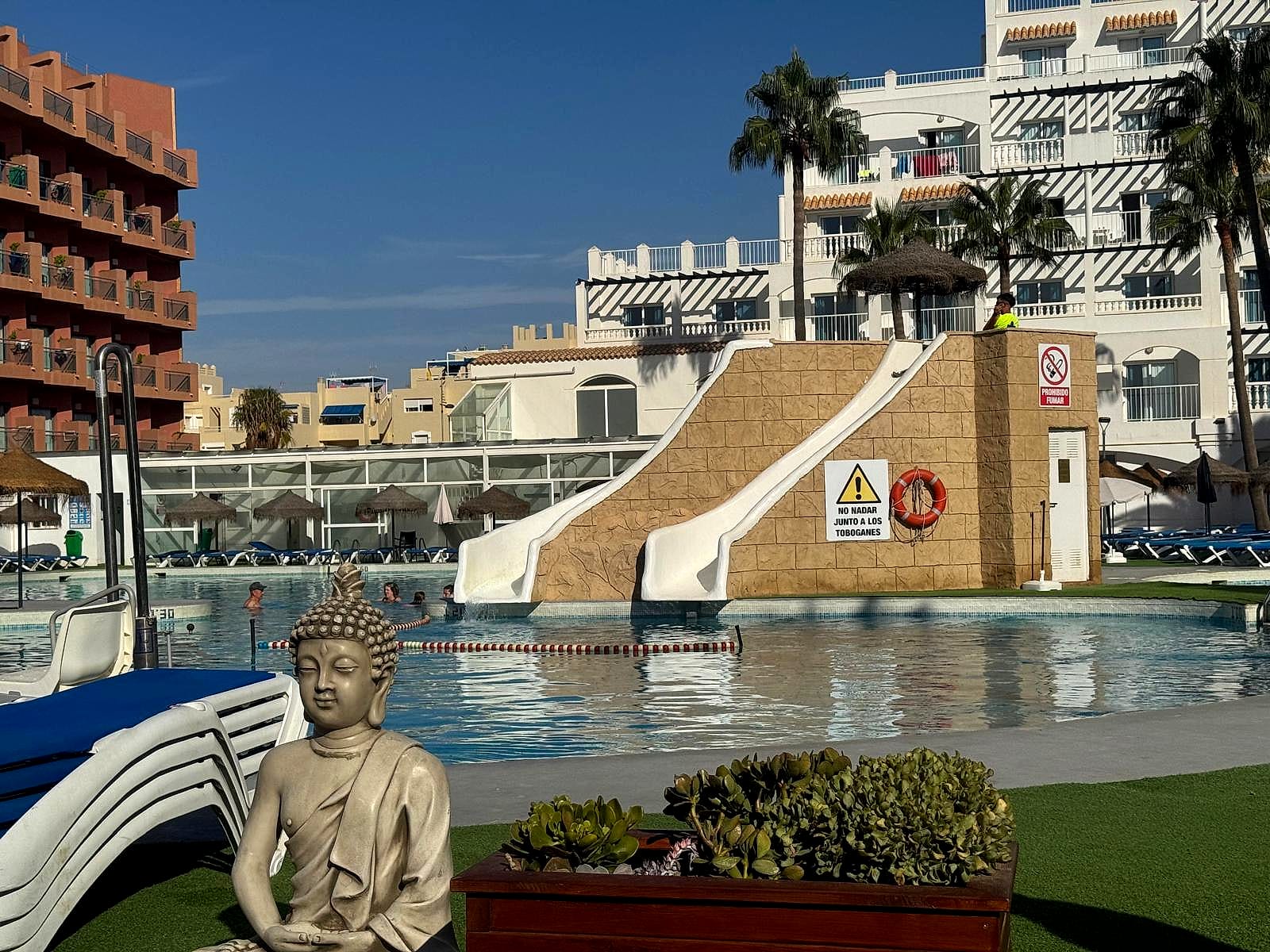 Los dos toboganes de la piscina del Hotel Bahía Serena, con una corchera que separa la zona de llegada y una figura de Buda en primer plano