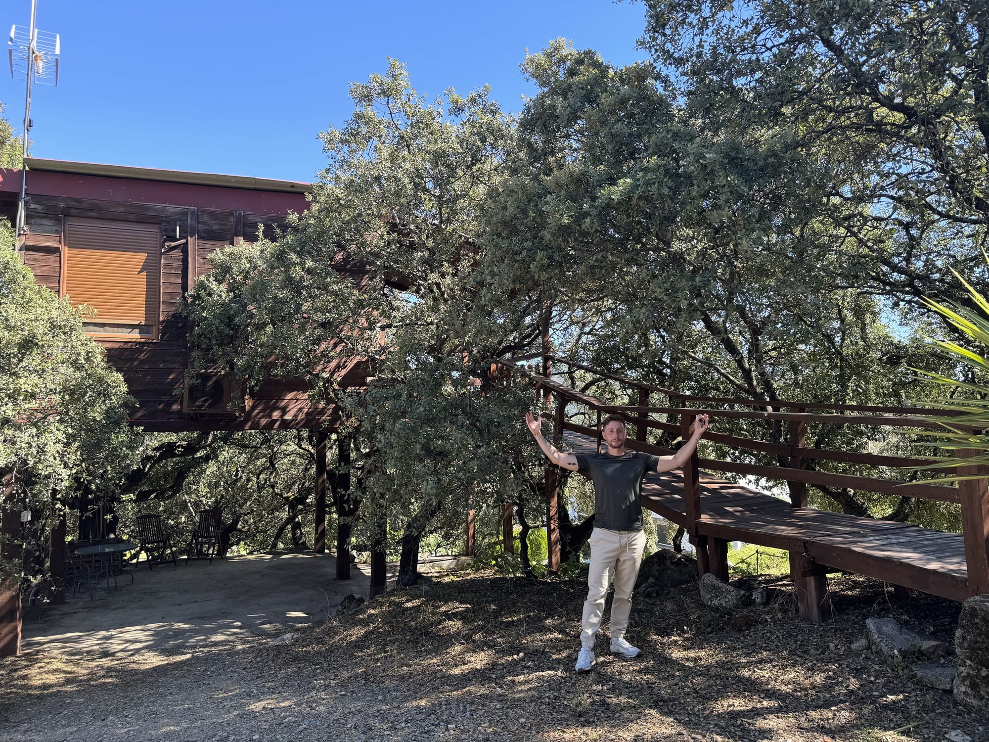 Cabaña en el árbol de Cabaña el Valle, entre encinas, con Javier Sobrino al pie de la pasarela
