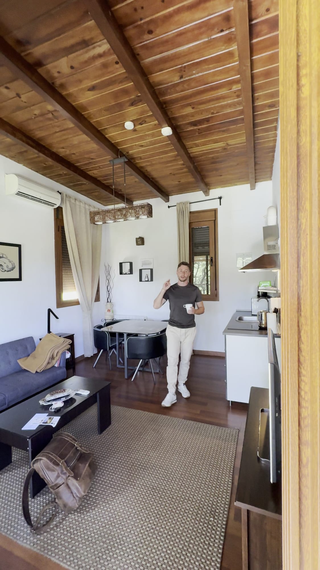 Salón con cocina y vigas de madera en una cabaña de Cabaña el Valle