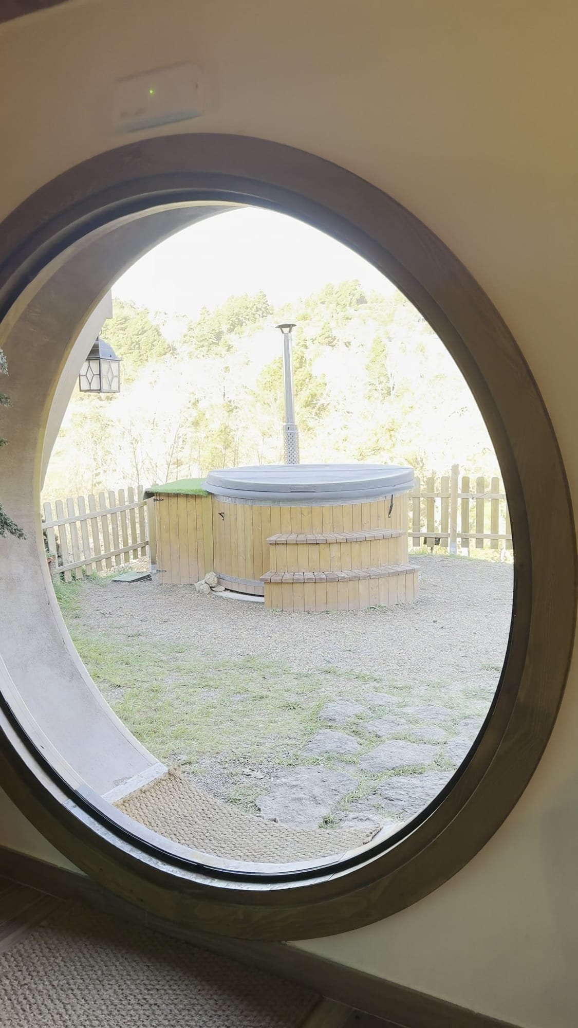 La tina de madera vista a través de la puerta redonda de la casita de La Comarca de Veratton