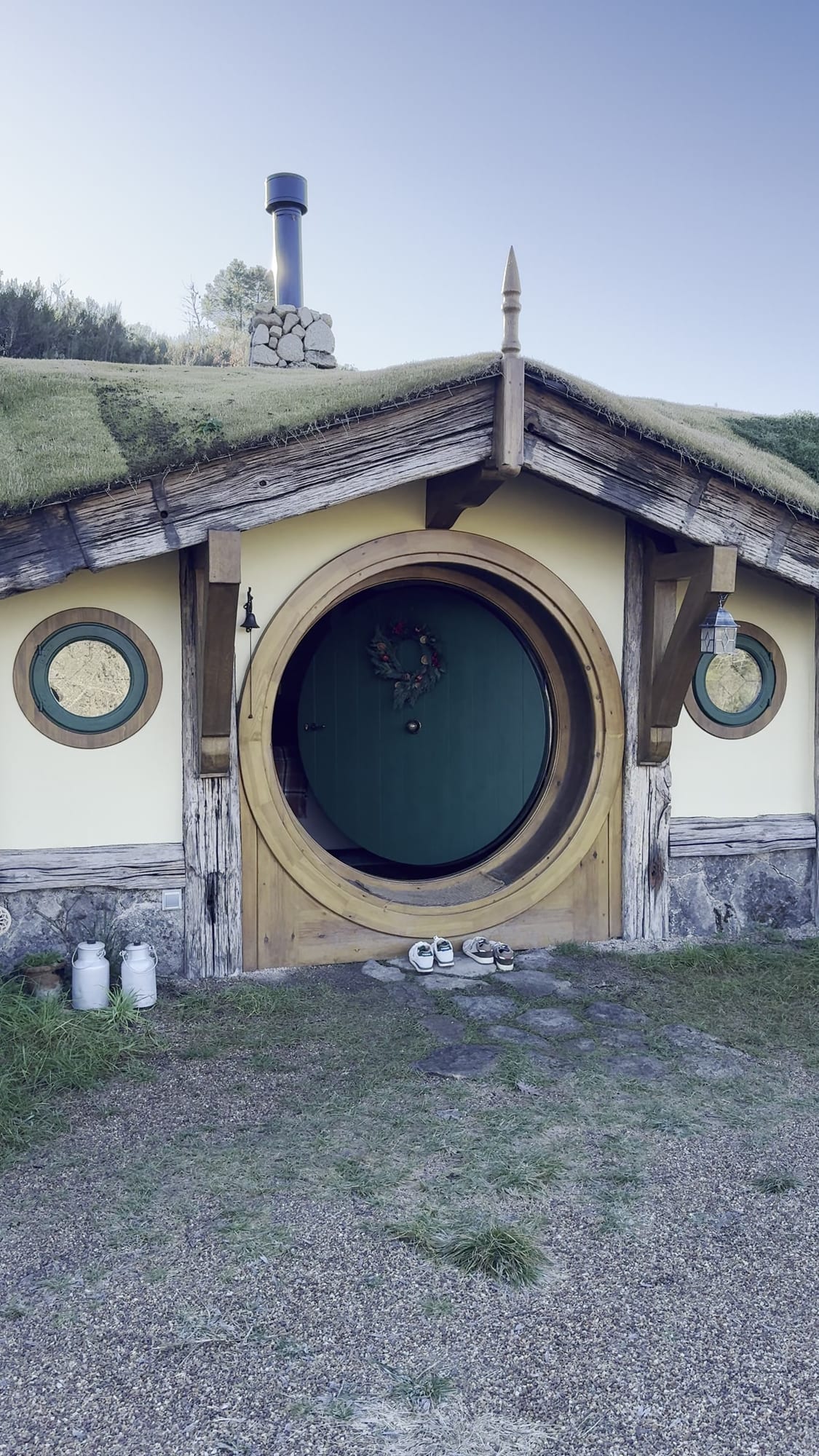 Casita hobbit de La Comarca de Veratton con la puerta redonda verde y el tejado de hierba