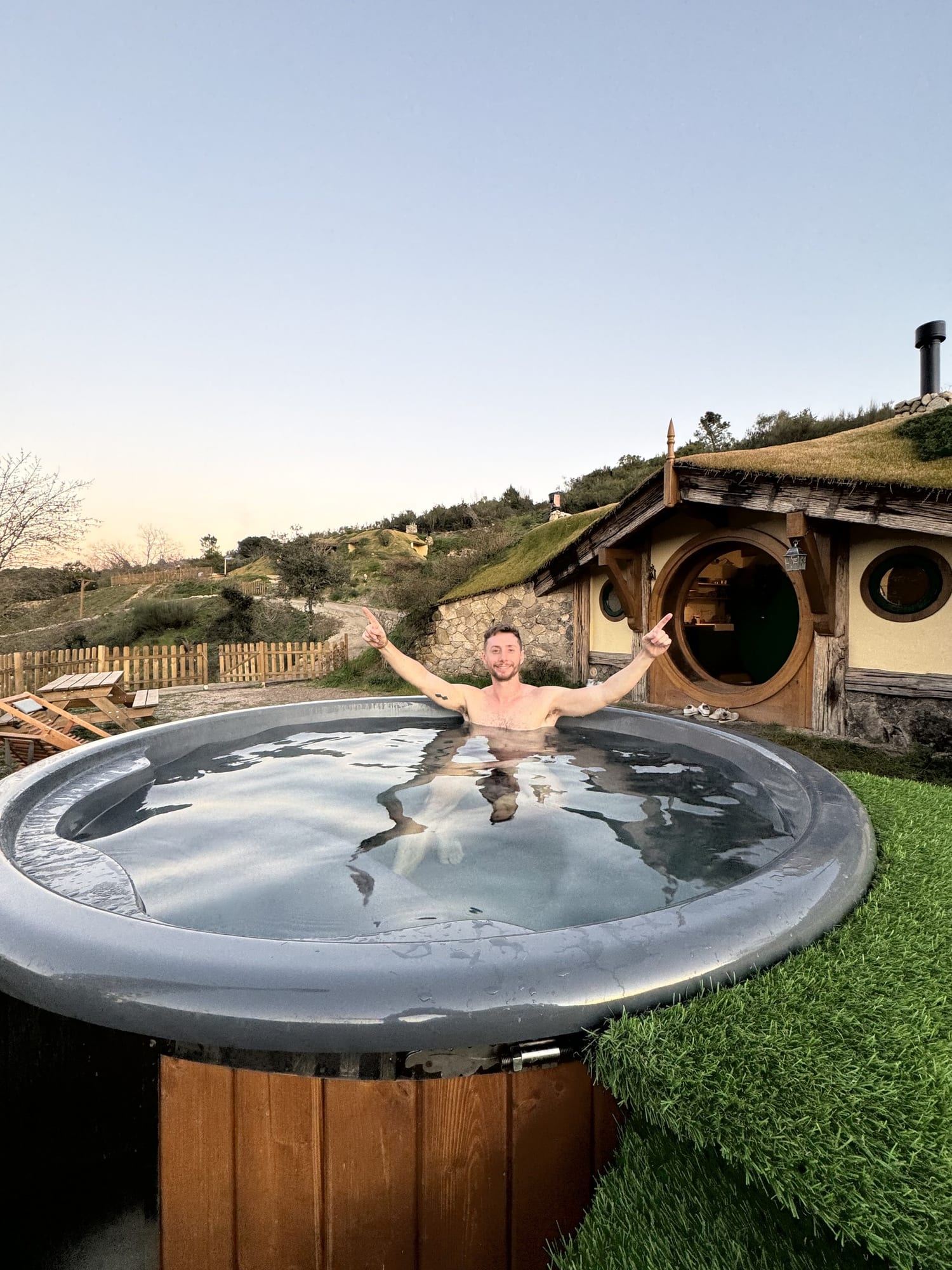 Javier Sobrino con los brazos abiertos en la tina de agua caliente frente a la casita hobbit de La Comarca de Veratton