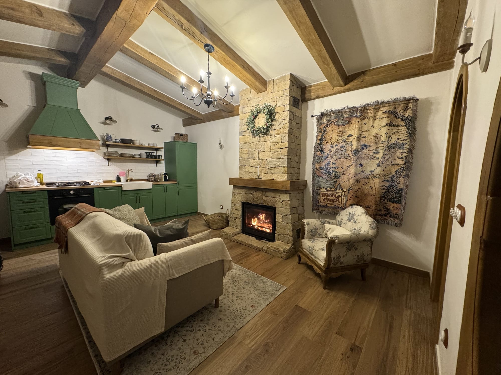 Salón de la casita de La Comarca de Veratton con la chimenea encendida y la cocina verde