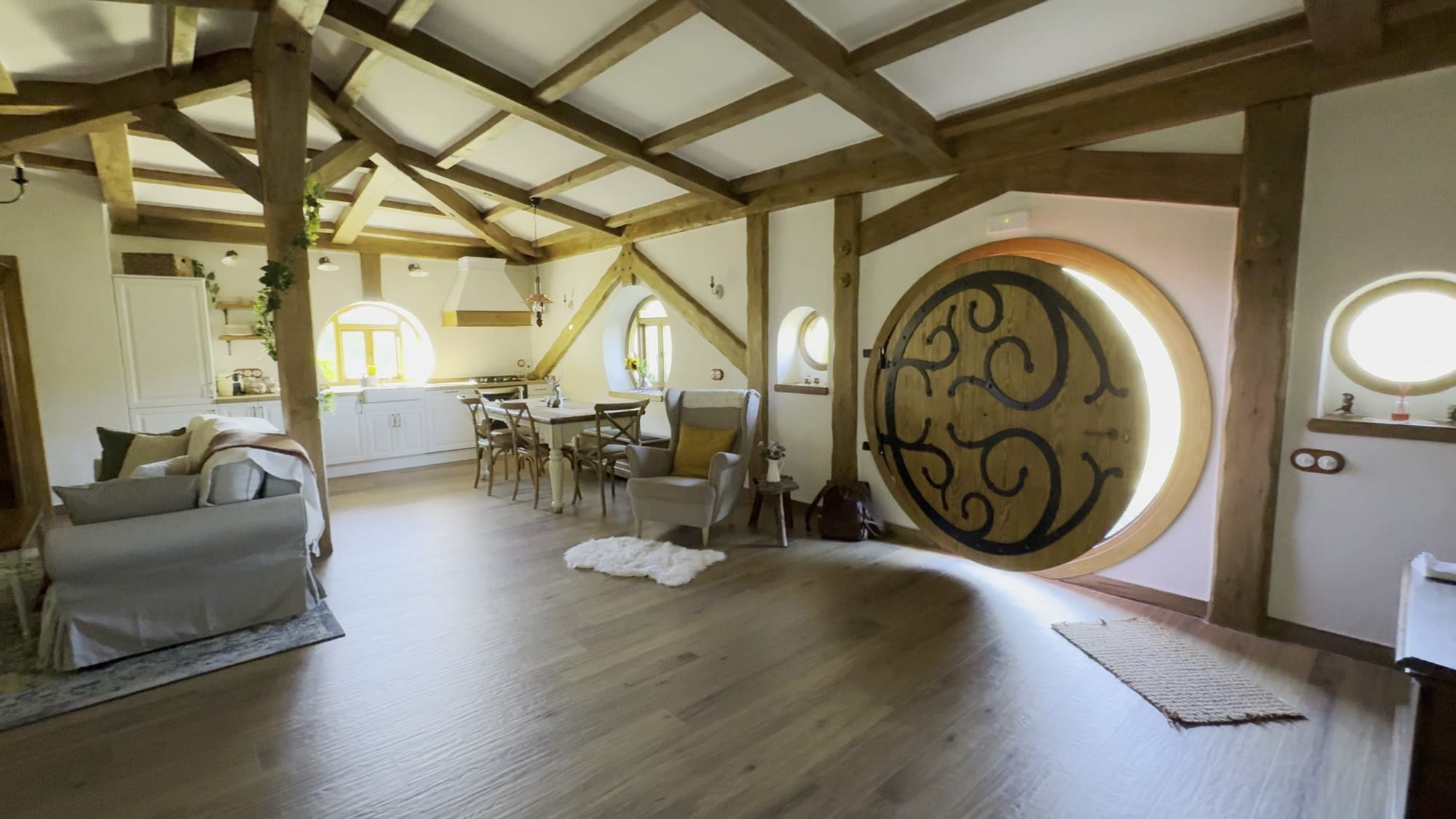 Salón comedor de La Comarca de Veratton con la puerta redonda de forja y vigas de madera