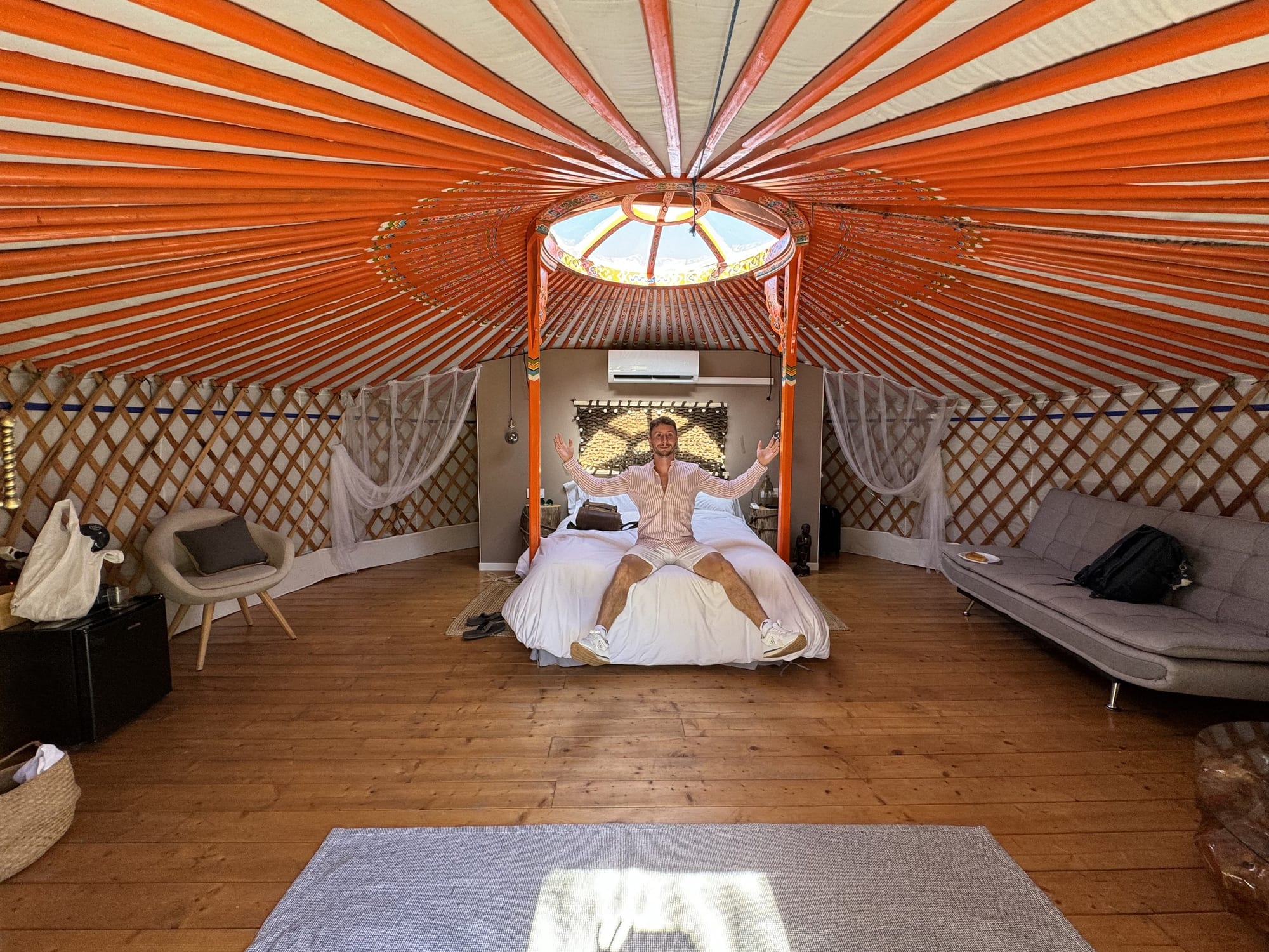 Interior de una yurta con cama doble, sofá y claraboya en El Jardín de las Delizias