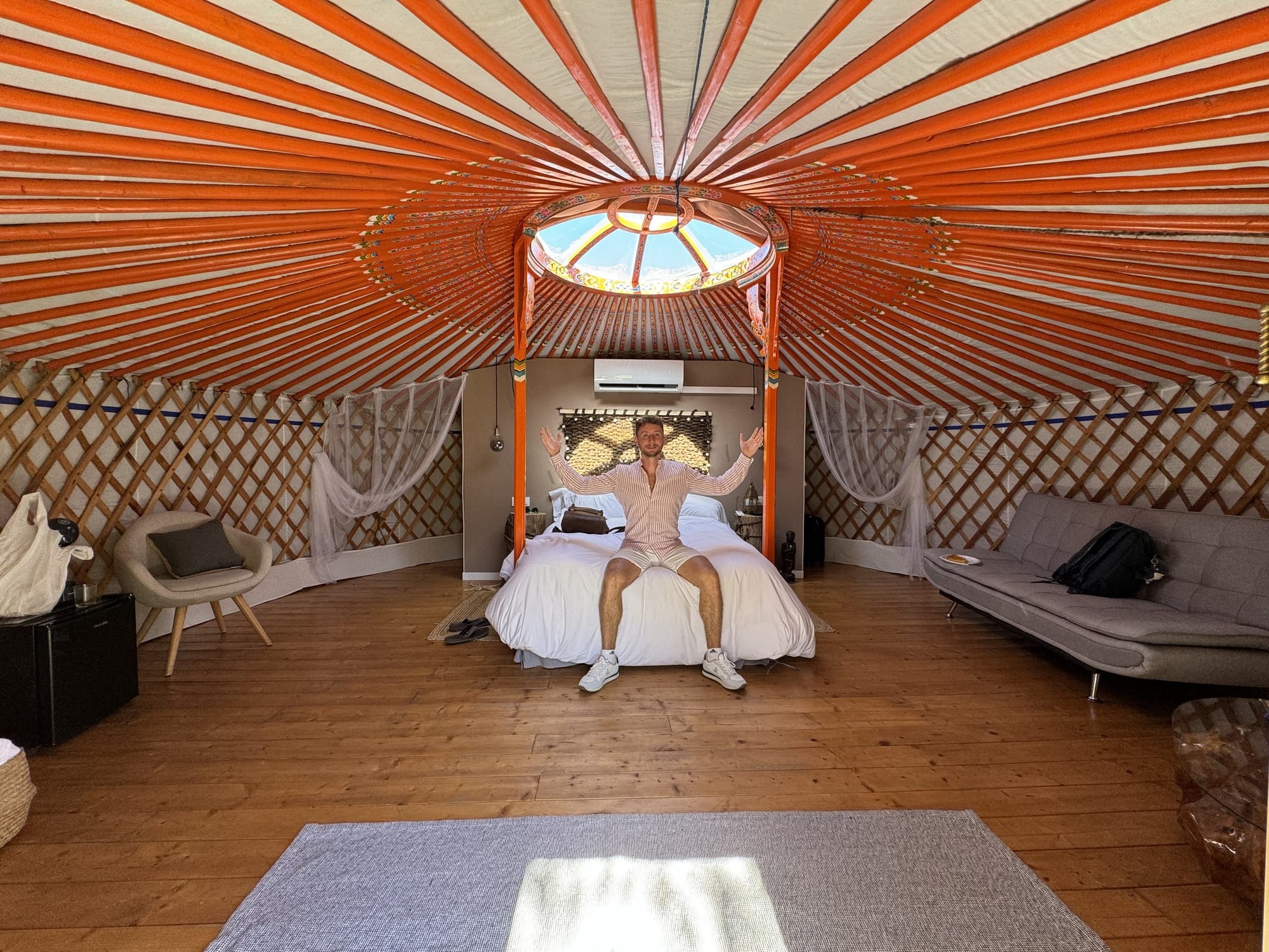 Javier Sobrino sentado en la cama de una yurta del Glamping El Jardín de las Delizias, bajo la claraboya