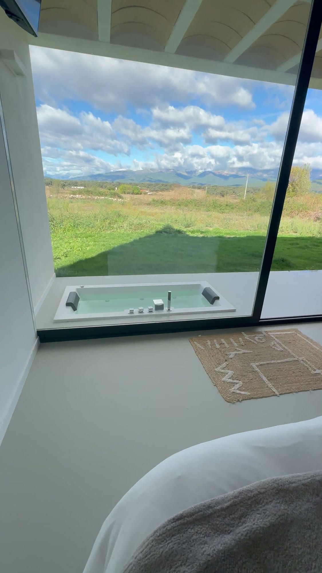 Vista desde la cama al jacuzzi exterior y la sierra en Estrellas de Gredos