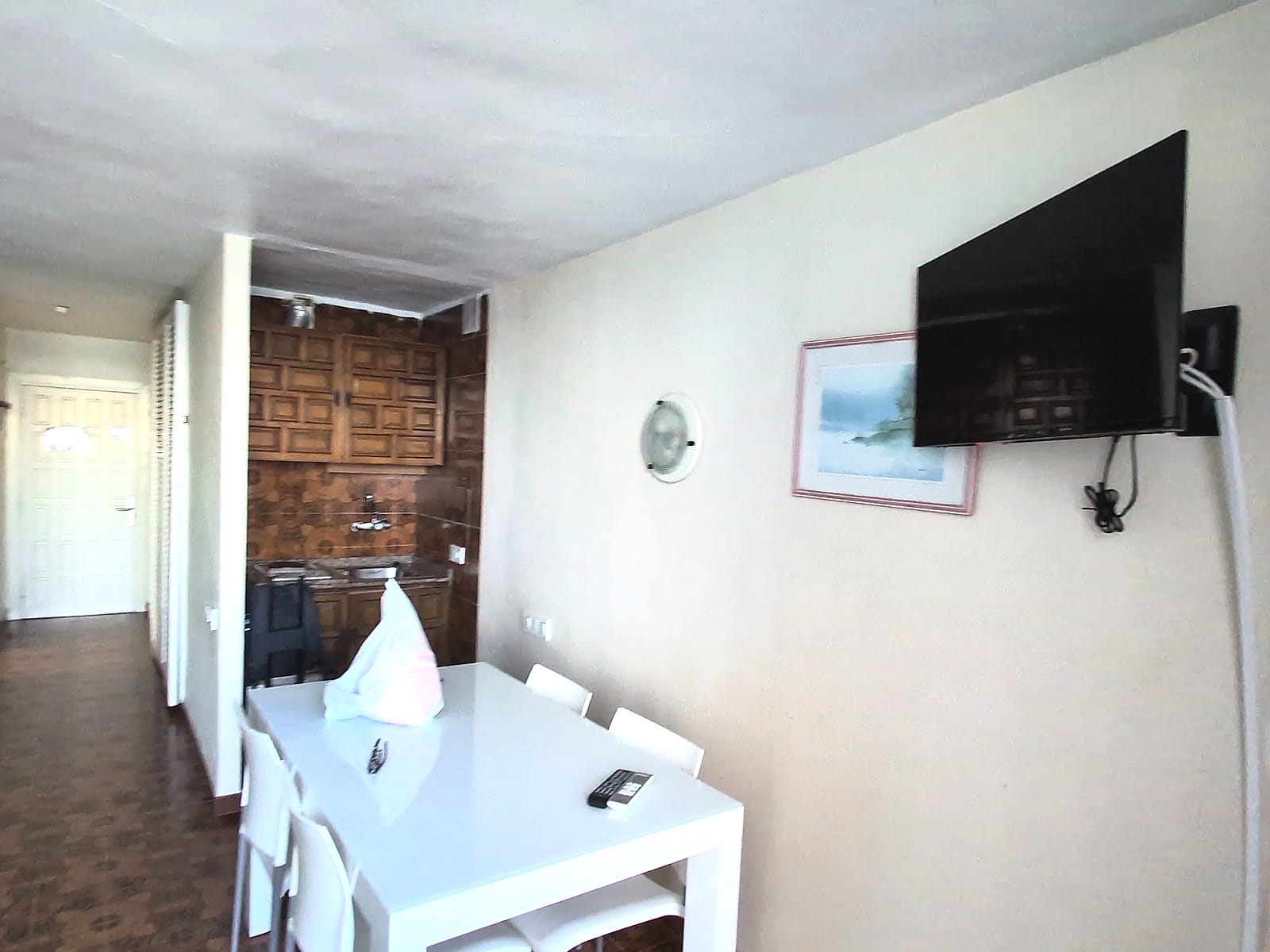El salón del estudio del Eurhostal, con la mesa, la televisión y la cocina al fondo