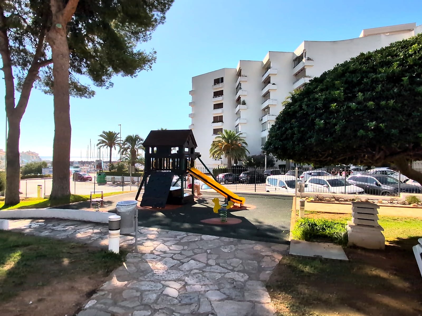 El parque infantil del Eurhostal, con una torre de madera y un tobogán, entre pinos