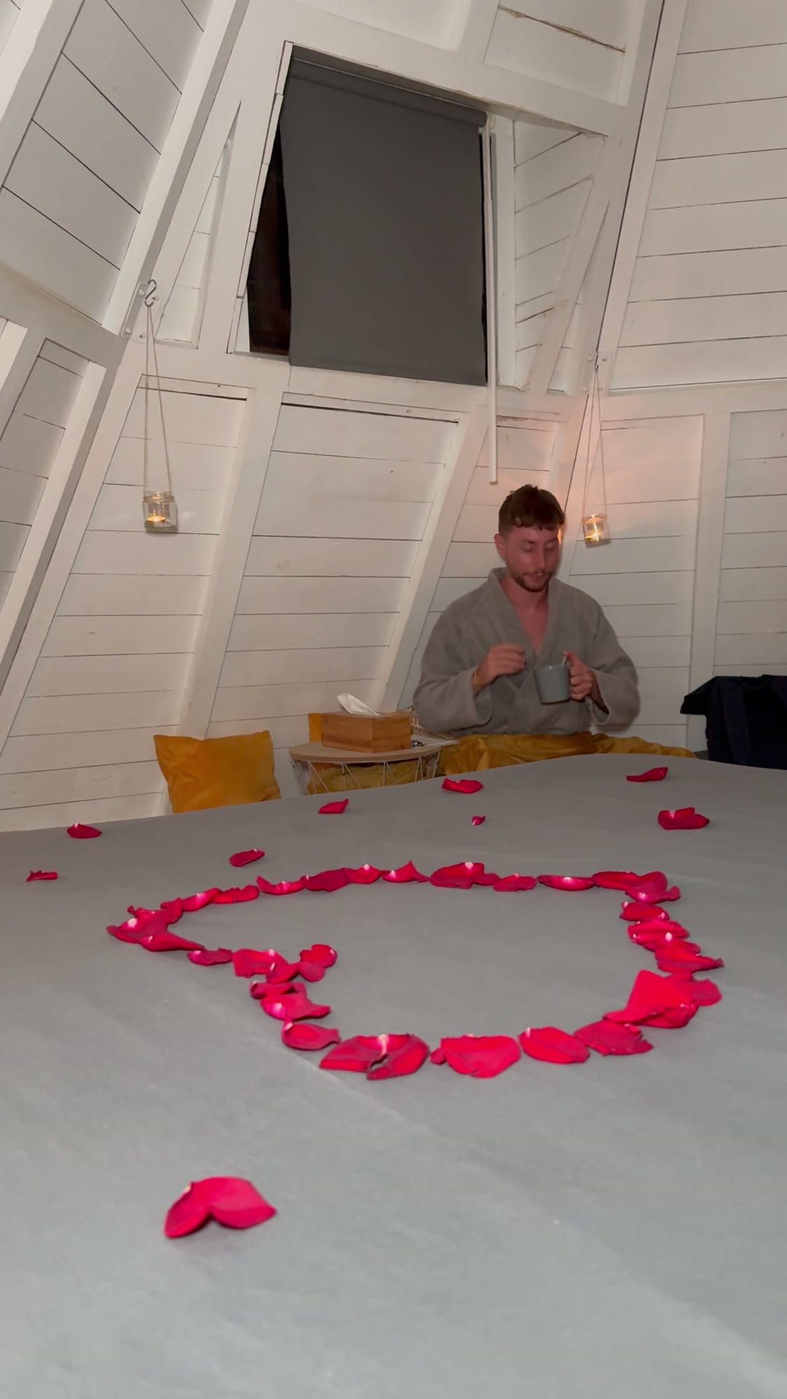 Javier Sobrino en la cama del tipi con un corazón de pétalos de rosa en el Glamping The Teepee
