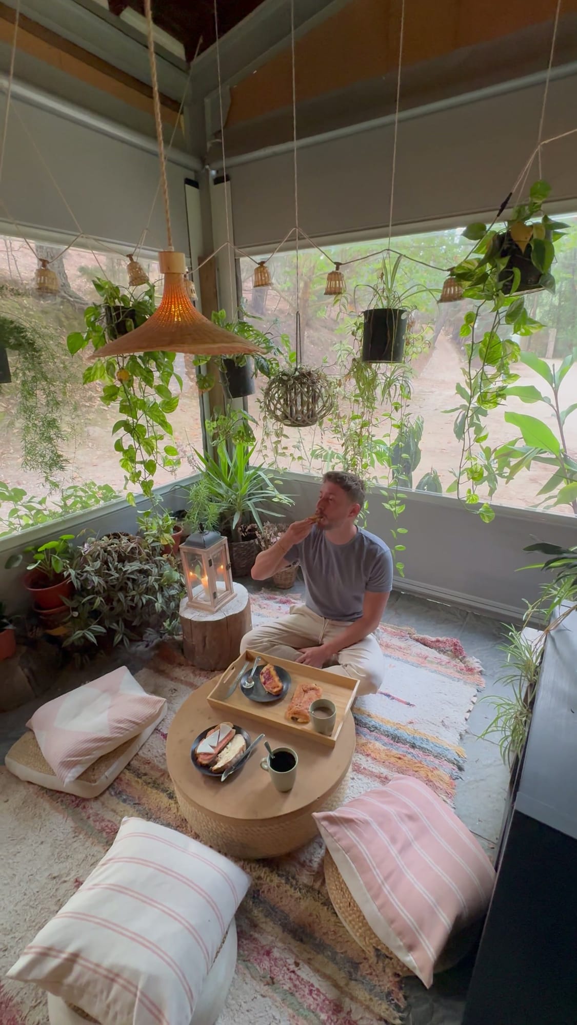 Rincón de desayuno con plantas colgantes y cojines en el suelo del Glamping The Teepee