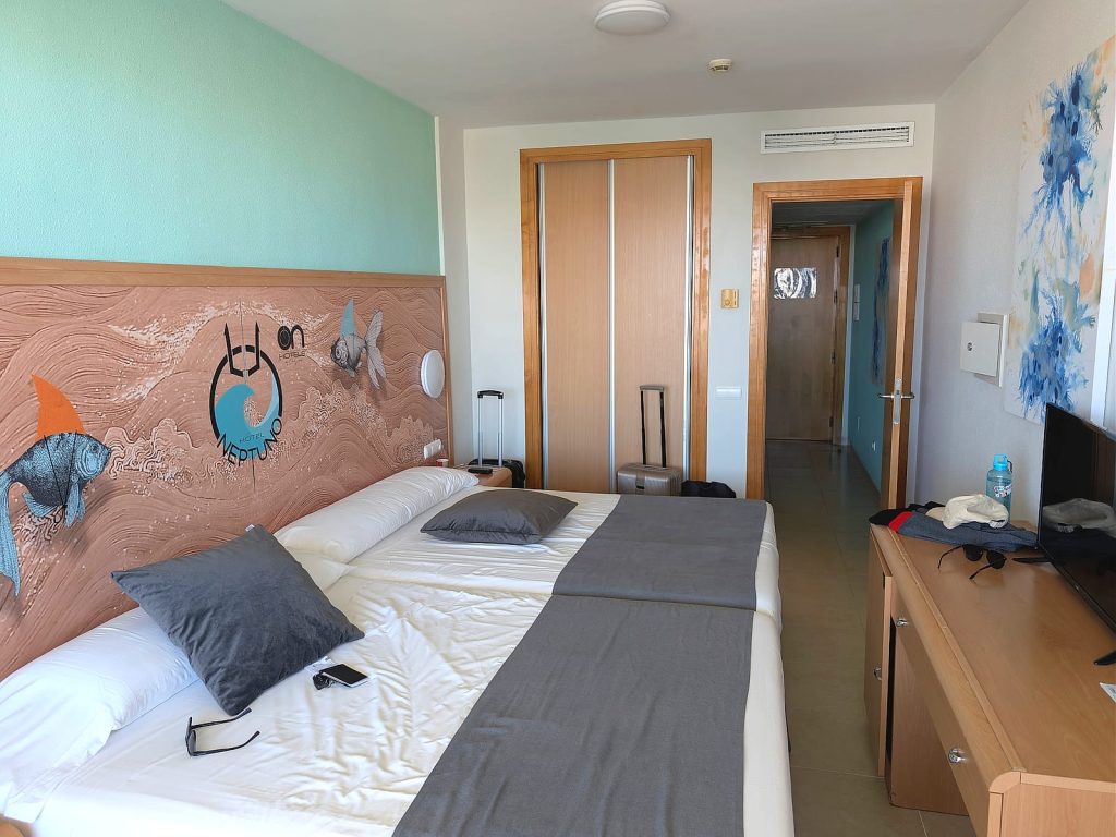 La habitación doble estándar del Hotel Neptuno, con dos camas y el mural del hotel en el cabecero