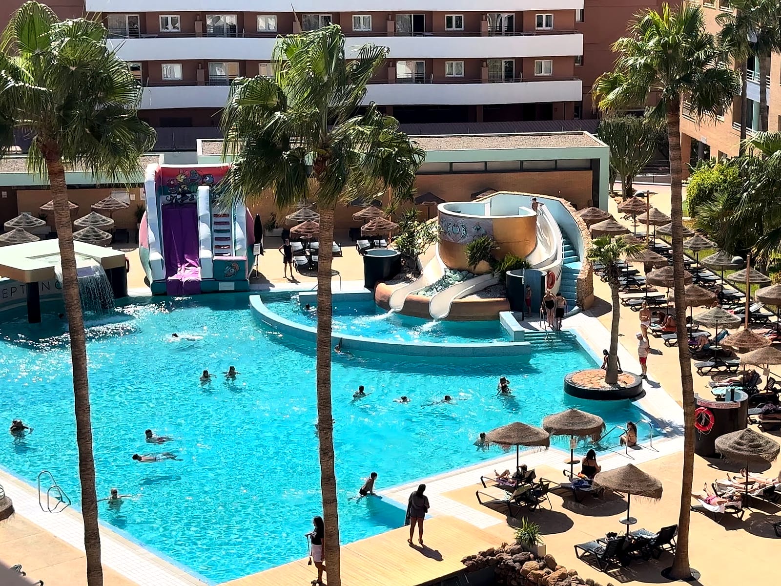 La piscina principal del Hotel Neptuno vista desde arriba, con la torre de toboganes y las sombrillas