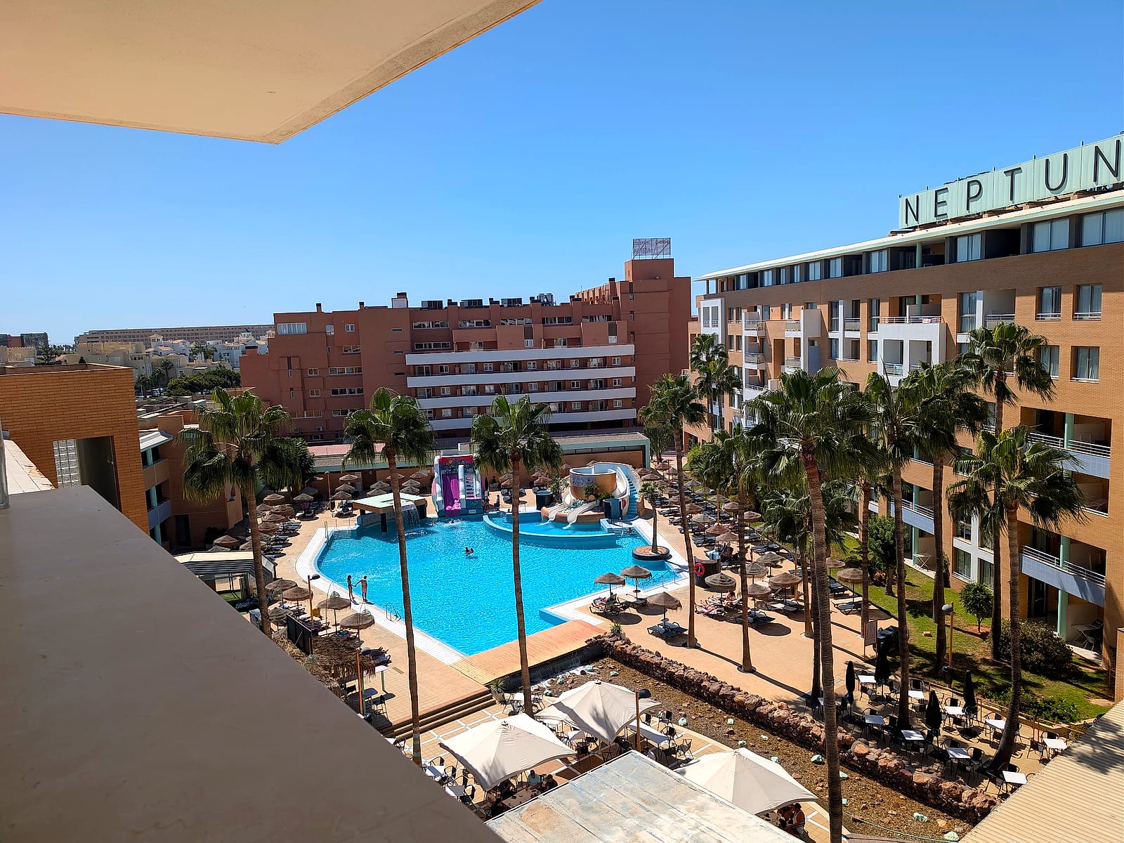 La piscina del Hotel Neptuno vista desde una planta alta, con el letrero del hotel en el edificio