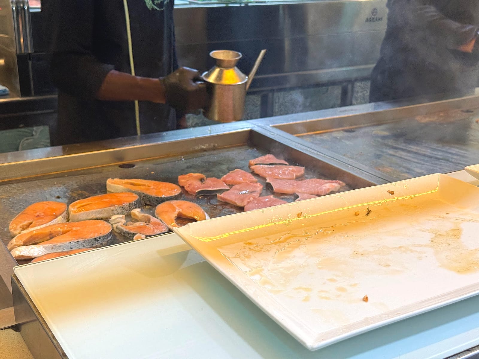 Salmón y otros pescados en la plancha de la cocina en vivo del buffet del Hotel Neptuno