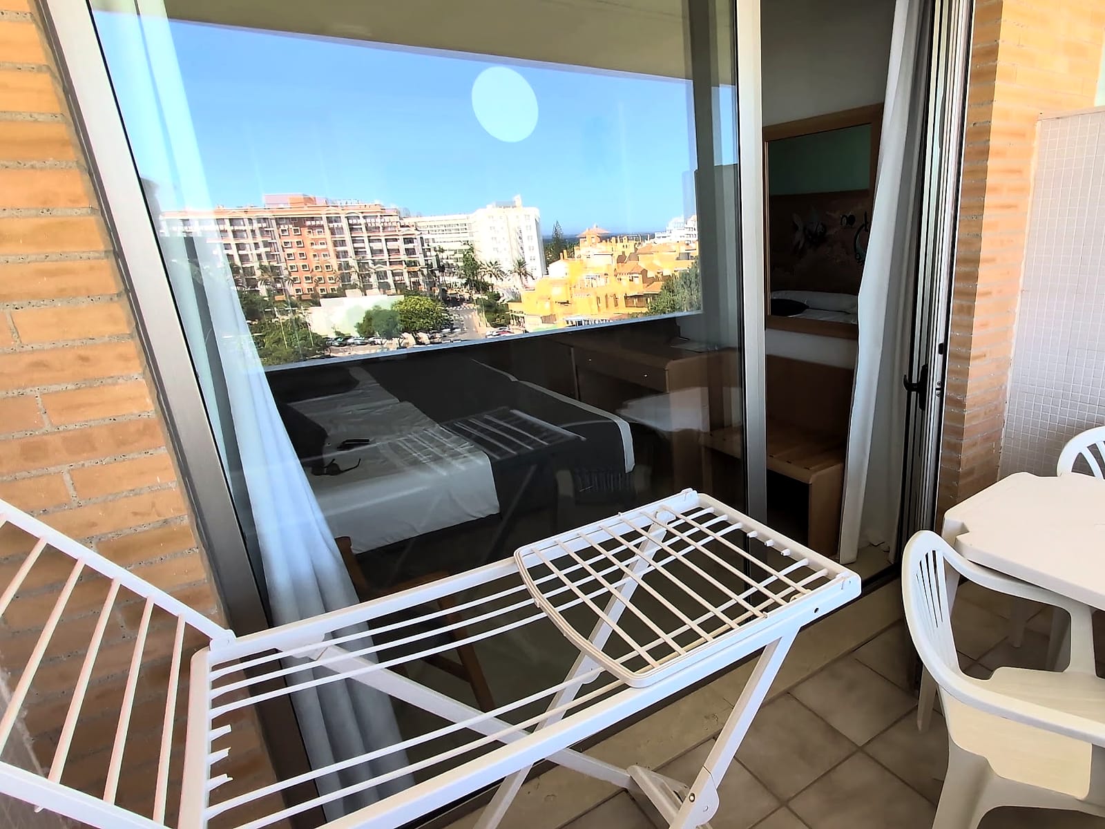 La terraza de la habitación del Hotel Neptuno, con mesa, sillas y tendedero