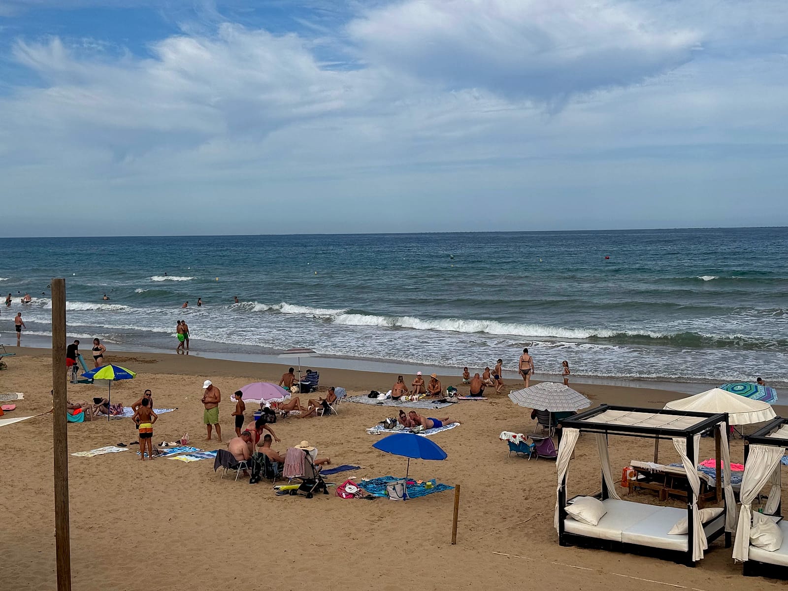 Camas balinesas de alquiler y sombrillas de los bañistas en la playa del Moncayo, en Guardamar