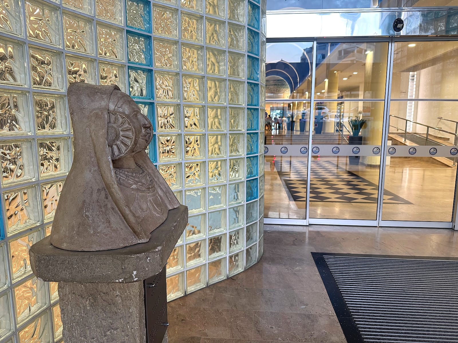La entrada del Hotel Playas de Guardamar, con una pared de pavés y una escultura de piedra