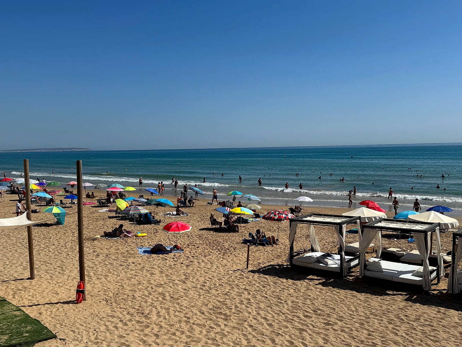 La playa del Moncayo por la mañana, con sombrillas de colores de los bañistas y camas balinesas