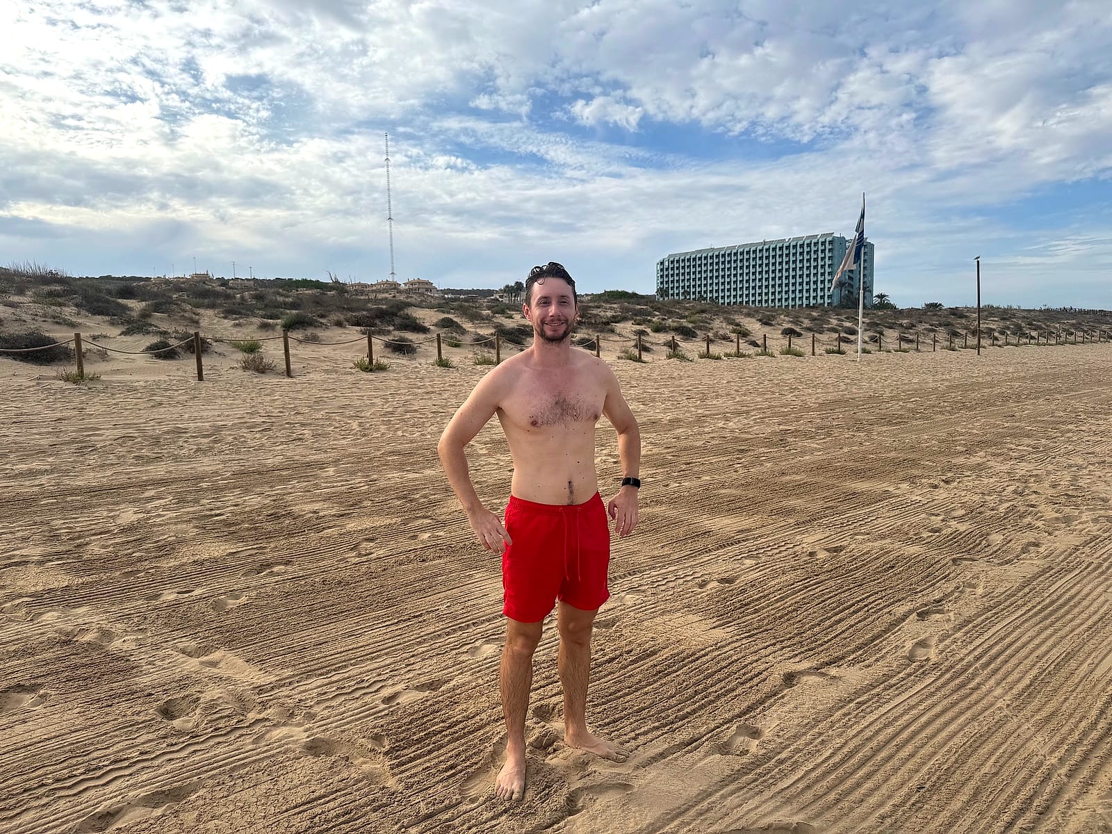 Javier Sobrino en la playa del Moncayo, ancha y de arena fina, con las dunas y el hotel al fondo