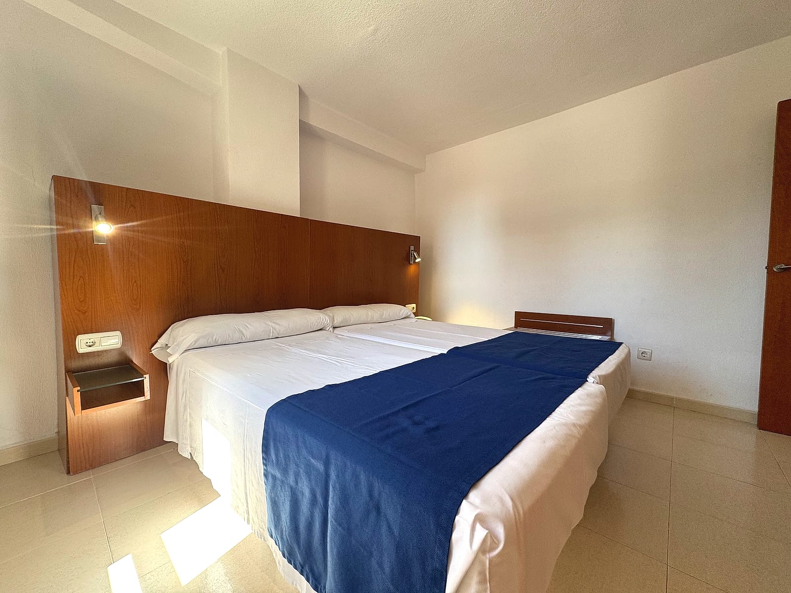 Uno de los dormitorios de la habitación familiar del Hotel Playas de Torrevieja, con cabecero de madera