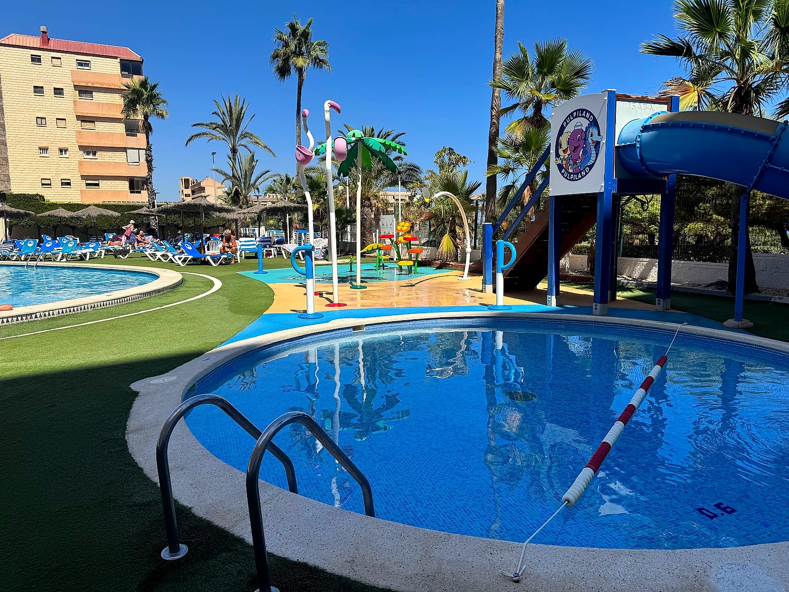 La piscina infantil del Hotel Playas de Torrevieja, redonda, con el tobogán azul detrás