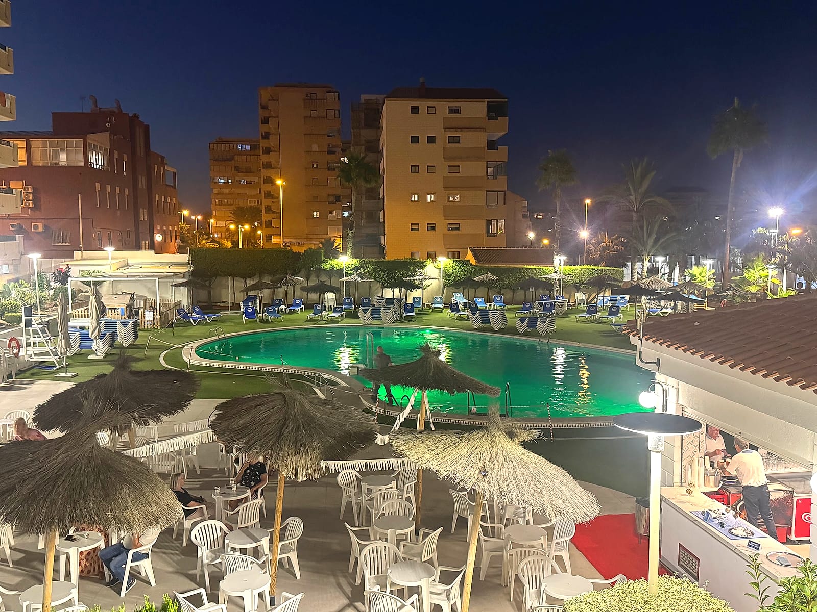 La piscina del Hotel Playas de Torrevieja de noche, iluminada, junto al bar de la terraza