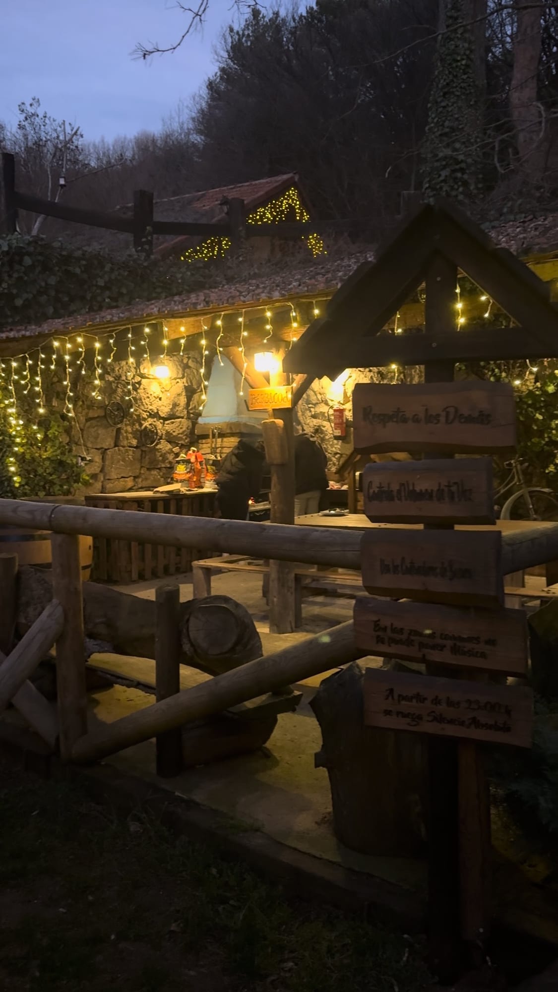 Carteles de madera y porche con guirnaldas de luces por la noche en La Posada de Cercedilla