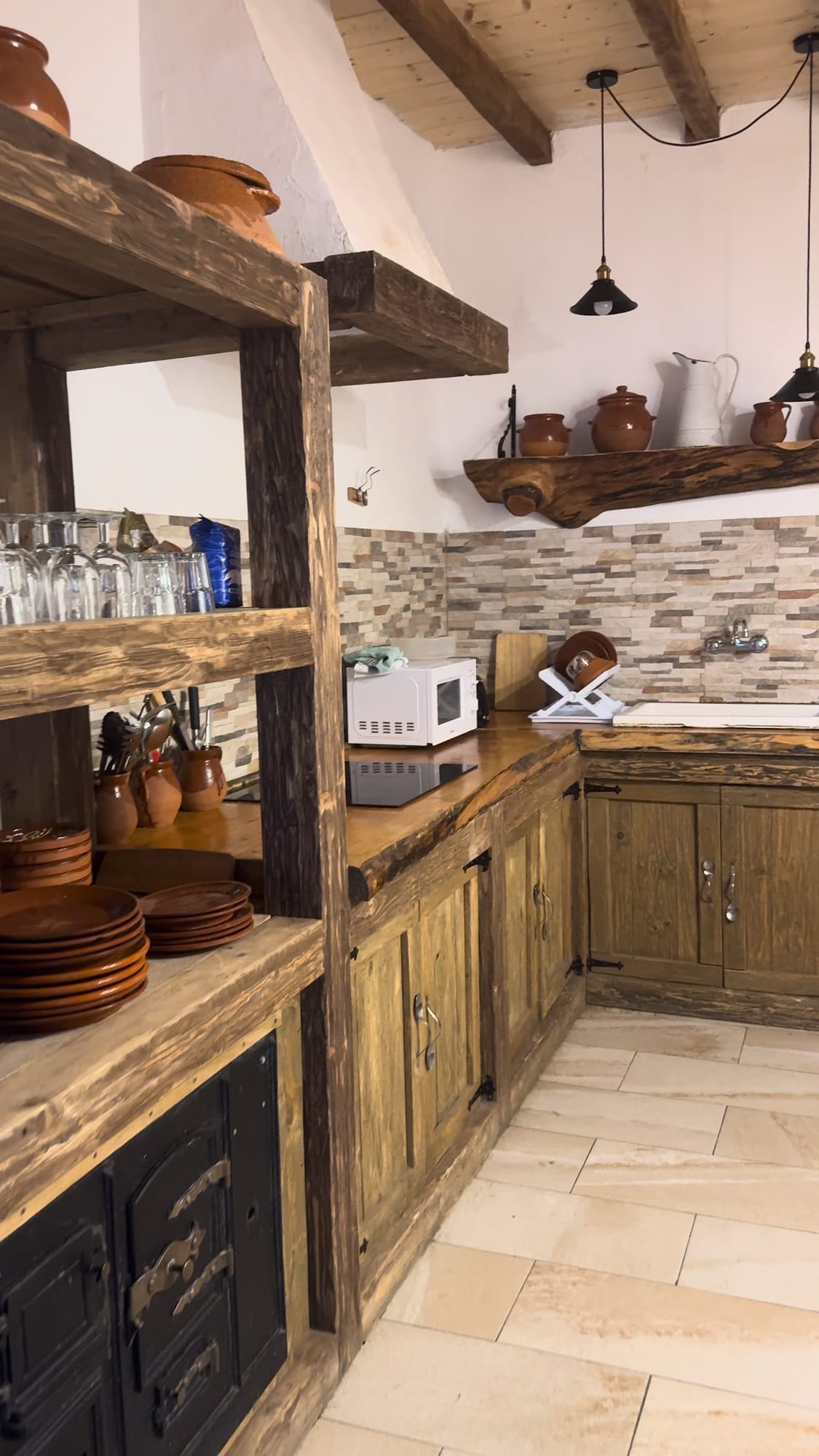 Cocina rústica con vajilla de barro y estantes de madera en La Posada de Cercedilla