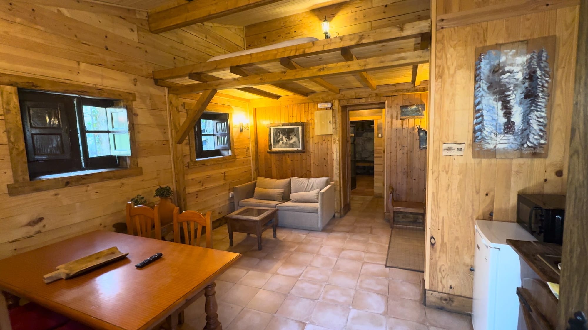 Salón comedor forrado de madera con sofá y mesa en La Posada de Cercedilla