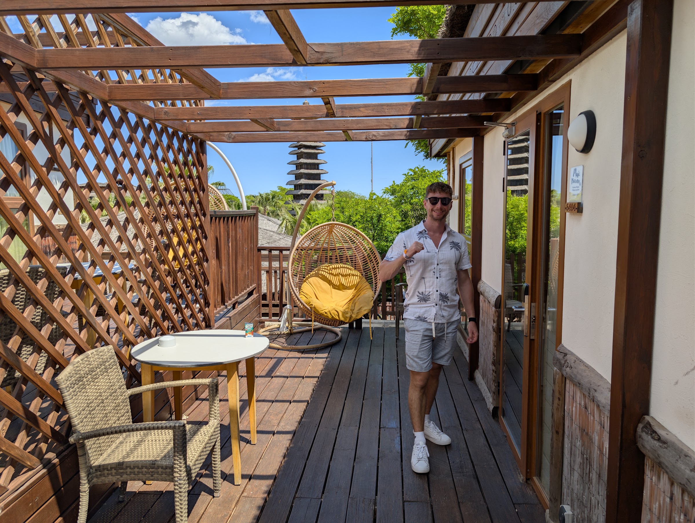 Terraza de madera de una cabaña del Magic Natura con sillón colgante y pérgola