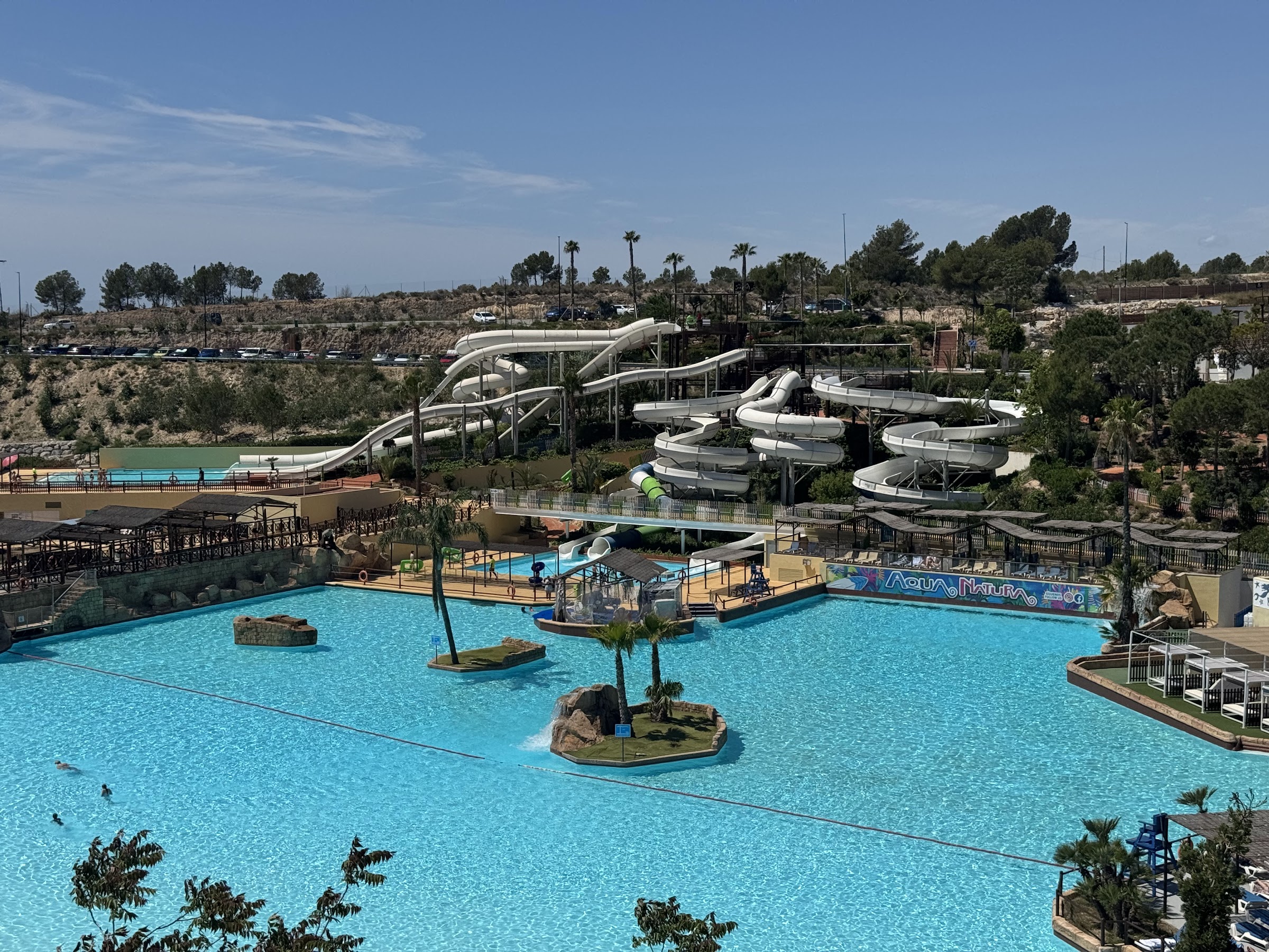 Lago turquesa con islotes y torres de toboganes de Aqua Natura Benidorm, junto al Magic Pirates Island