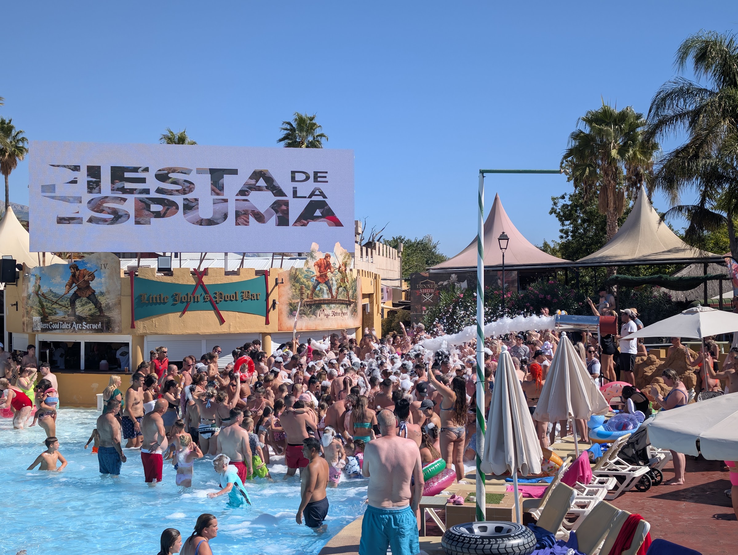 Pantalla de la fiesta de la espuma sobre el bar de la piscina del Magic Robin Hood, llena de gente