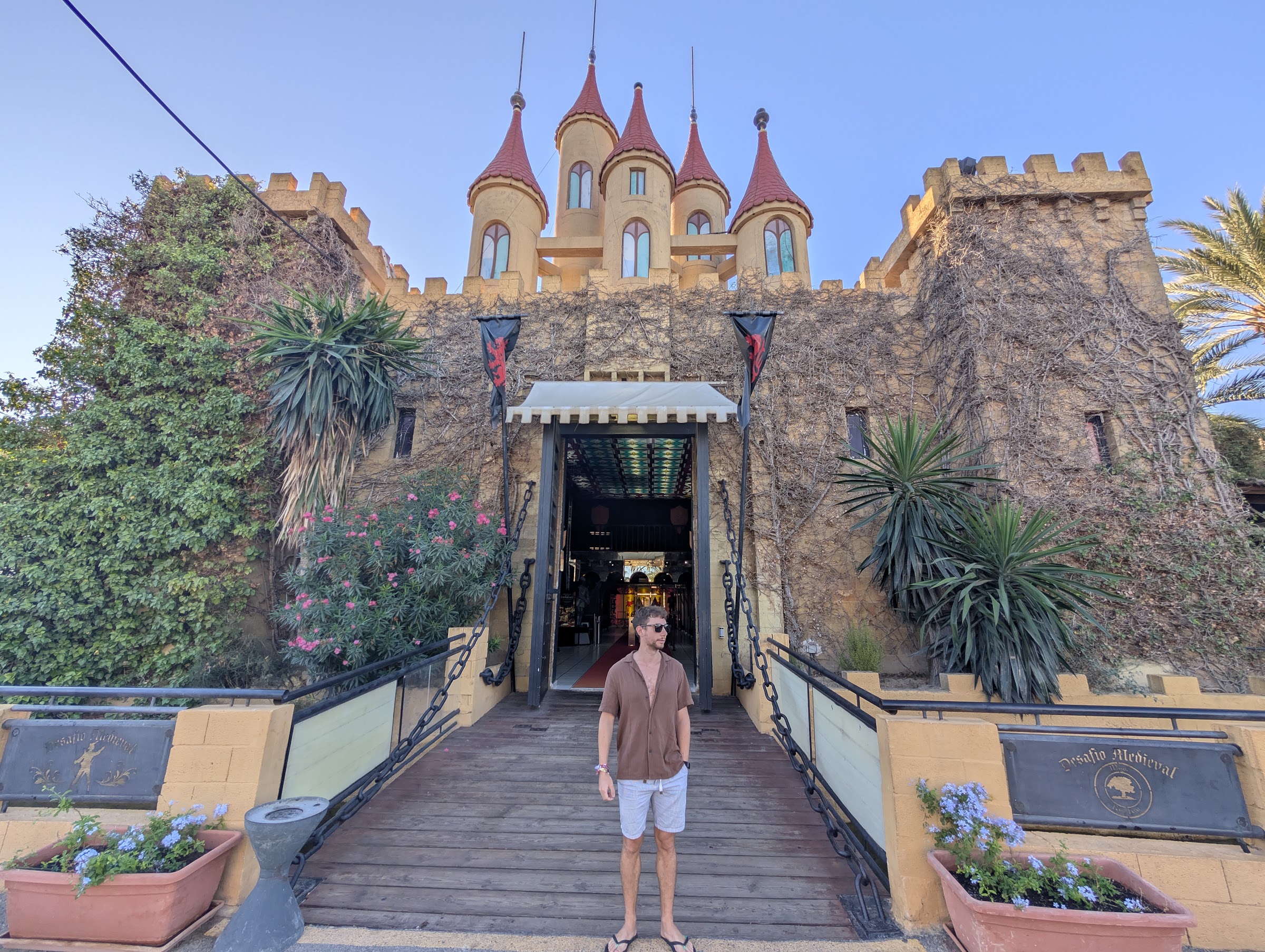 Entrada al castillo del Magic Robin Hood Resort con puente levadizo, torres rojas y estandartes