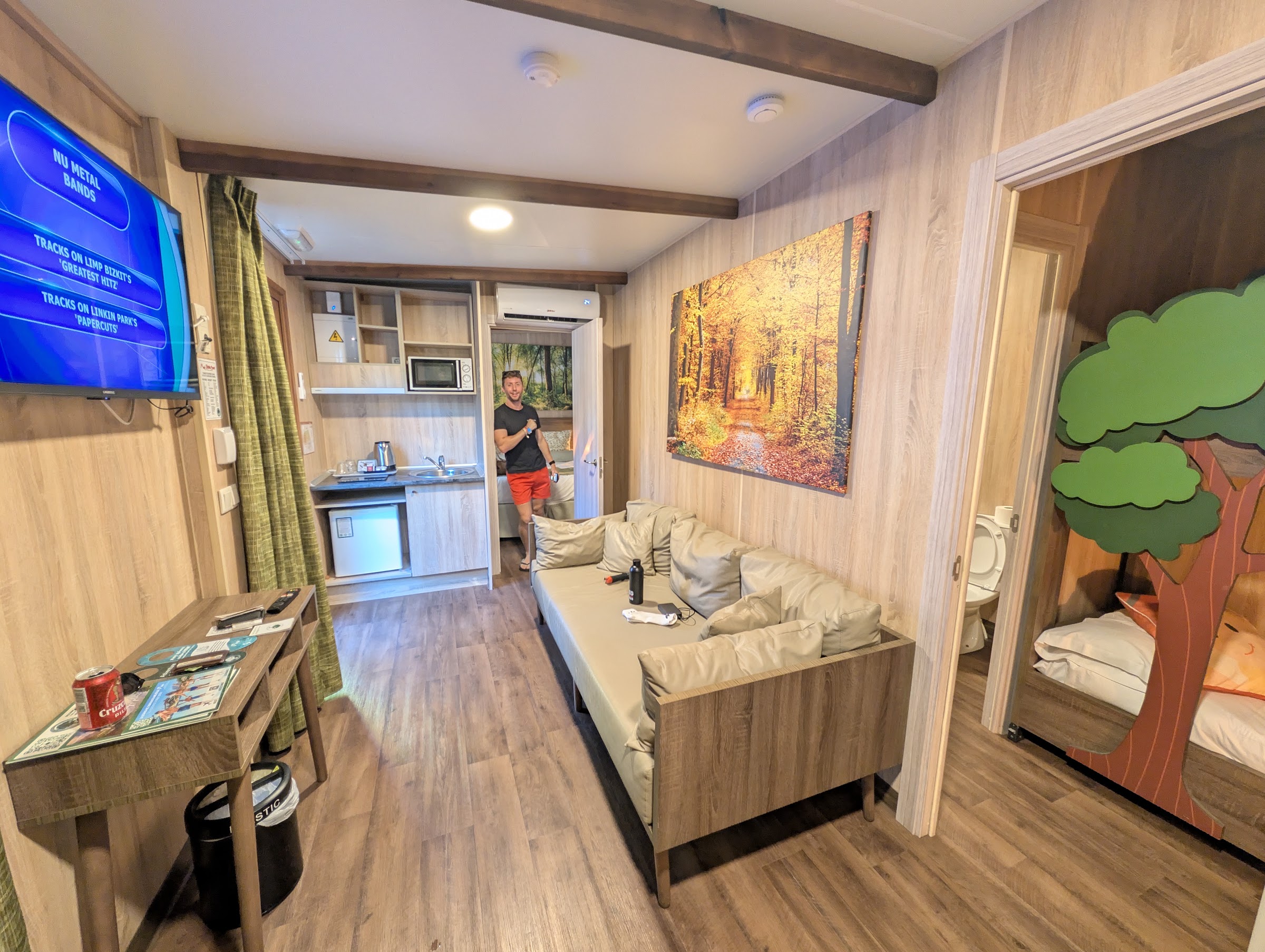 Cabaña del Magic Robin Hood con salón, cocina y habitación infantil decorada con un árbol