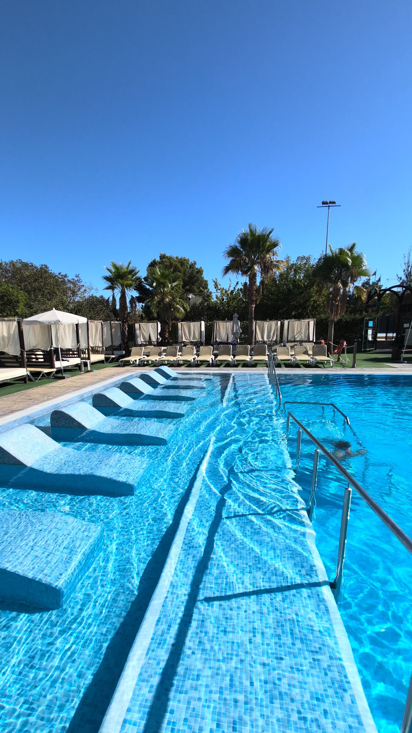Piscina con tumbonas sumergidas y camas balinesas al fondo en el Magic Robin Hood Resort